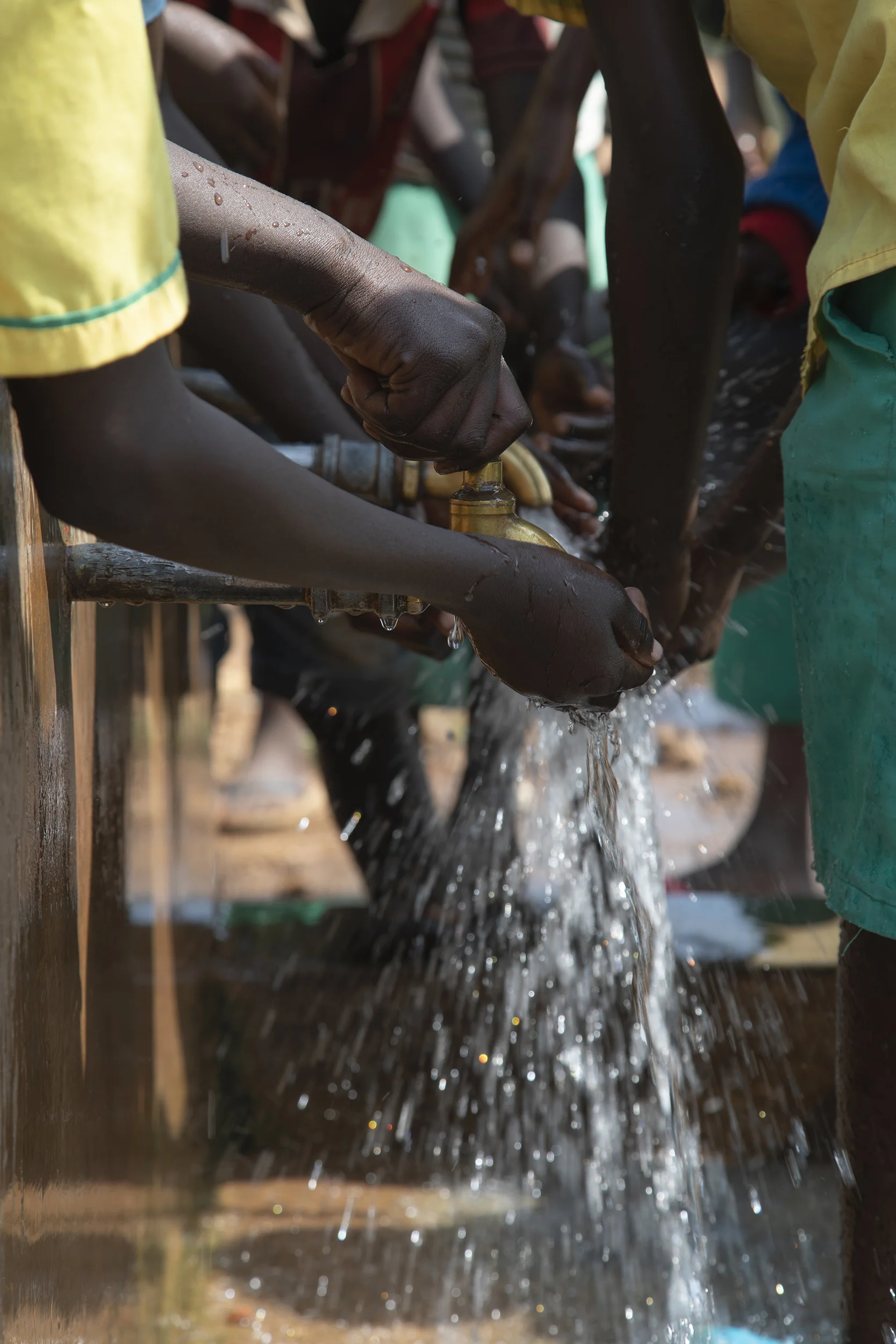 During a school break, students from Twajiji Primary School within Bidibidi Refugee Settlement drink from a public well.
