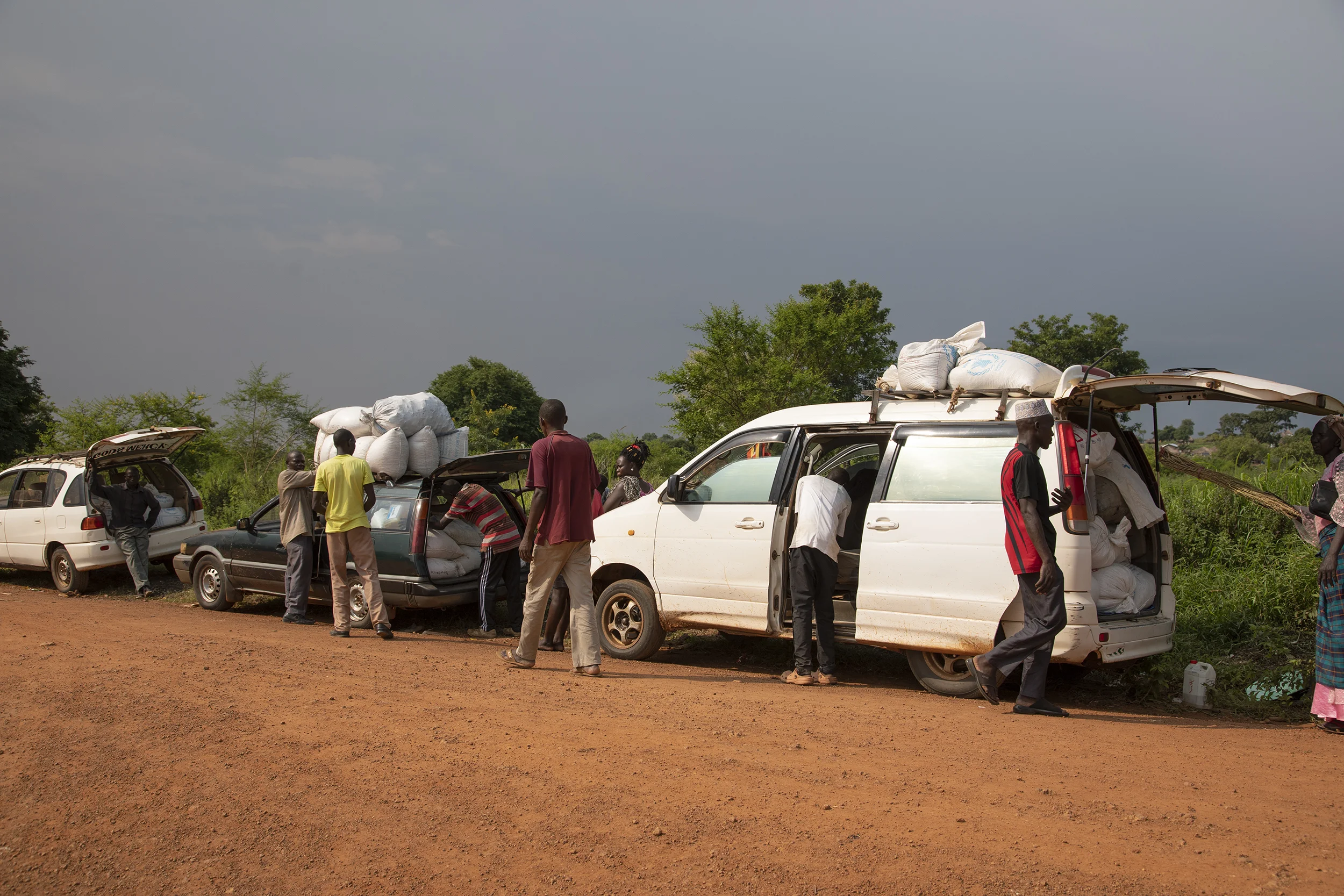 Near the food distribution centre at Zone 1 Bidibidi Refugee Settlement Northern Uganda. Families chip in together to hire cheap cars to transport their once-a-month food rations as distances are too far to carry such heavy bags.