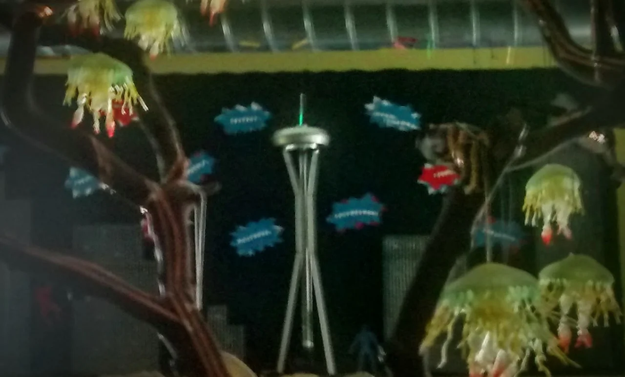 Space Needle Update: It’s alive! Long story short: Connecting two battery packs to a 12-volt blower at the bottom of the Space Needle elevator (an acorn vending capsule in the tube in the center) raises the elevator, which, once it hits the top, completes the circuit connecting a rainbow LED (glowing through a length of white core light pipe ) and a CR2032 battery . Shiny!