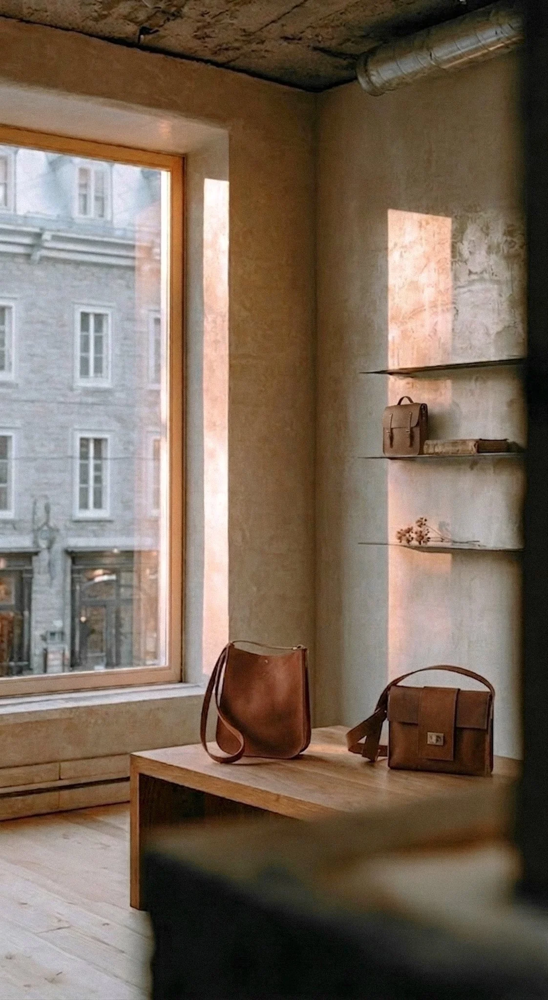Intérieur de la boutique de maroquinerie artisanale Les Mains d'ici dans le Vieux-Québec avec sacs en cuir exposés sur banc et étagères