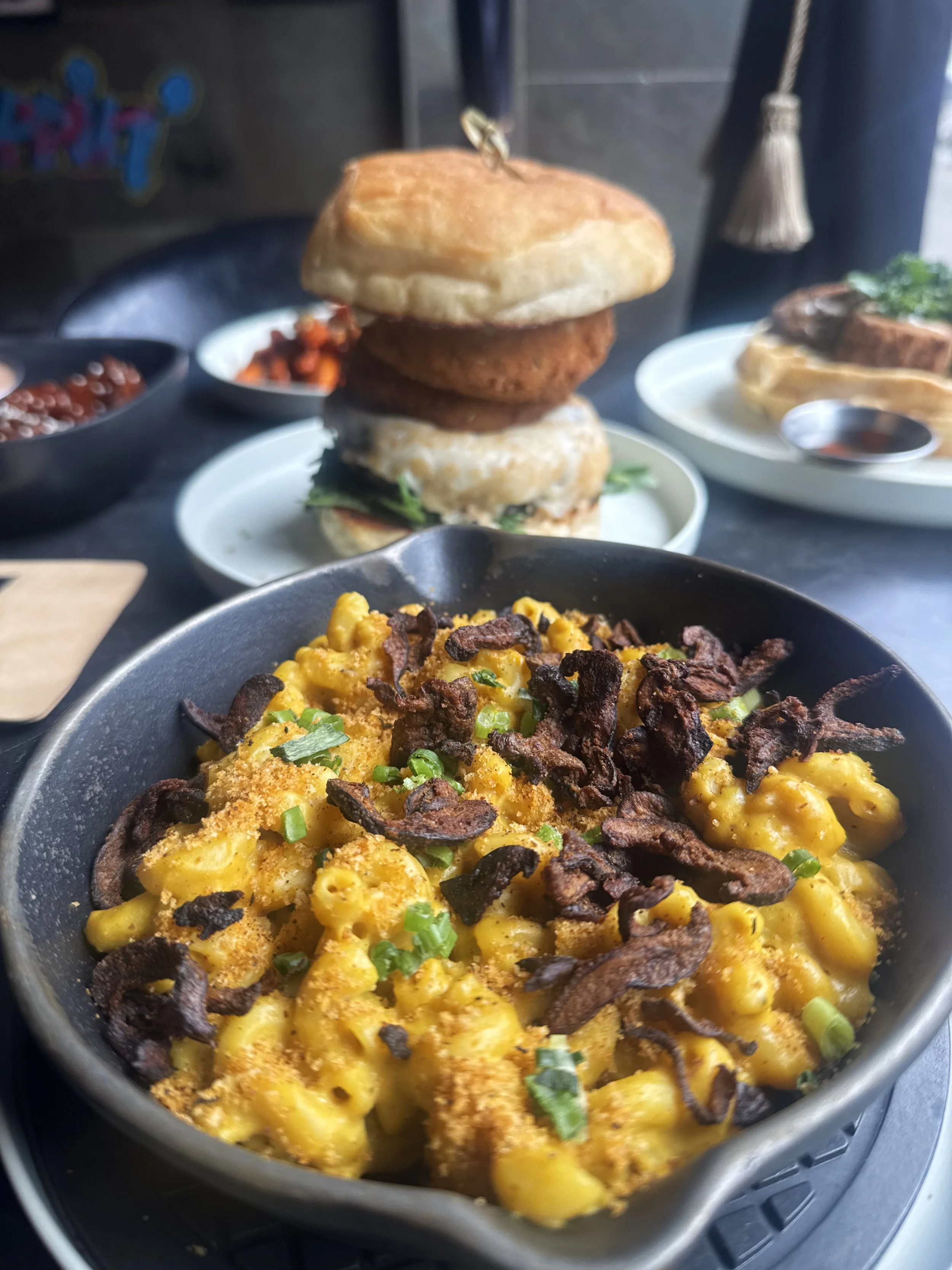 Vegan Illmatic Mac n’ Cheese at Urban Vegan Kitchen with housemade cashew cheese sauce, herbed bread crumbs and scallions, with the Magic Ring Burger and Chick-un & Waffles in the background.