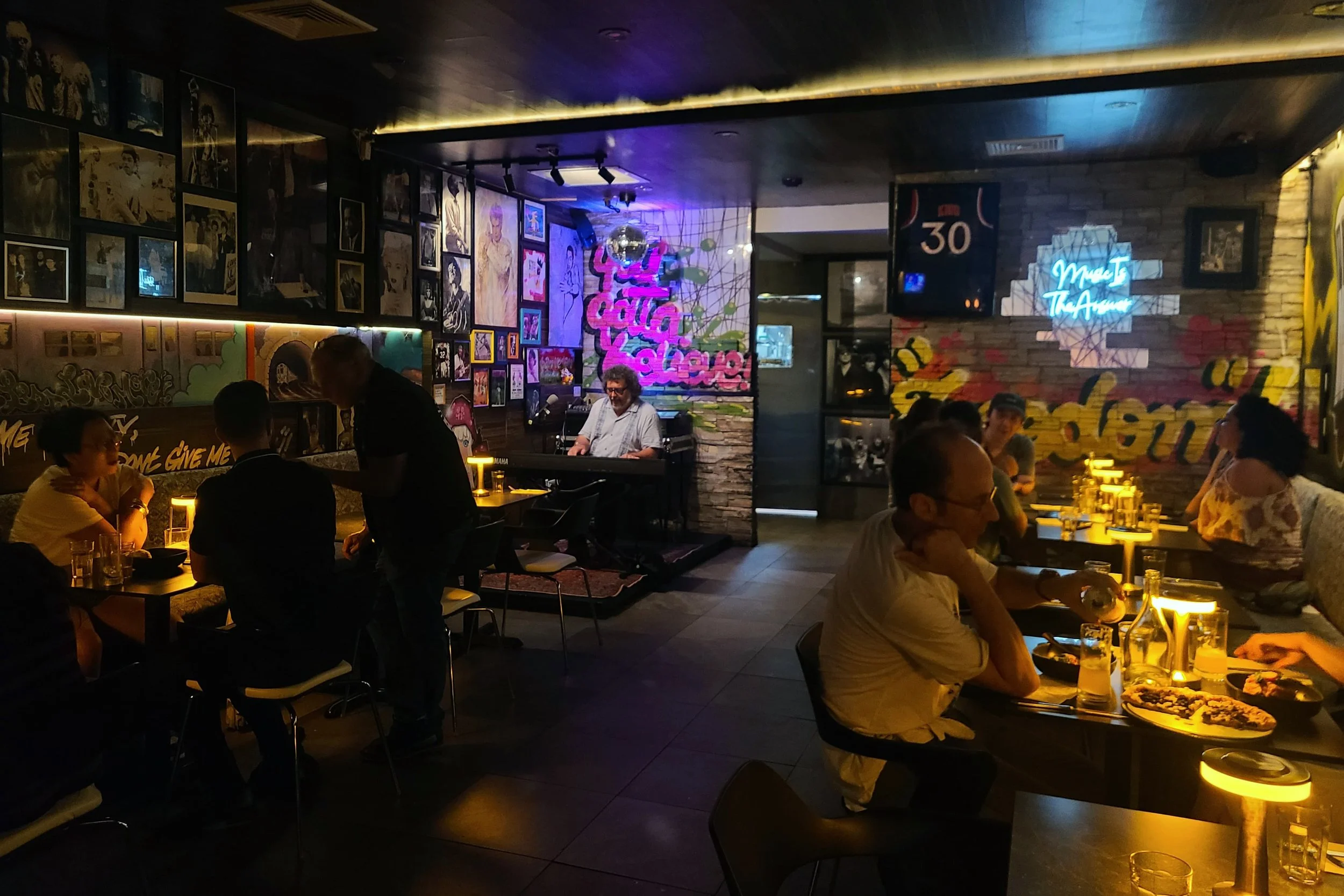 Live piano performance during Roots & Rebels Nights at Urban Vegan Kitchen, a vegan restaurant in Chelsea, NYC, with guests dining at dinner volume