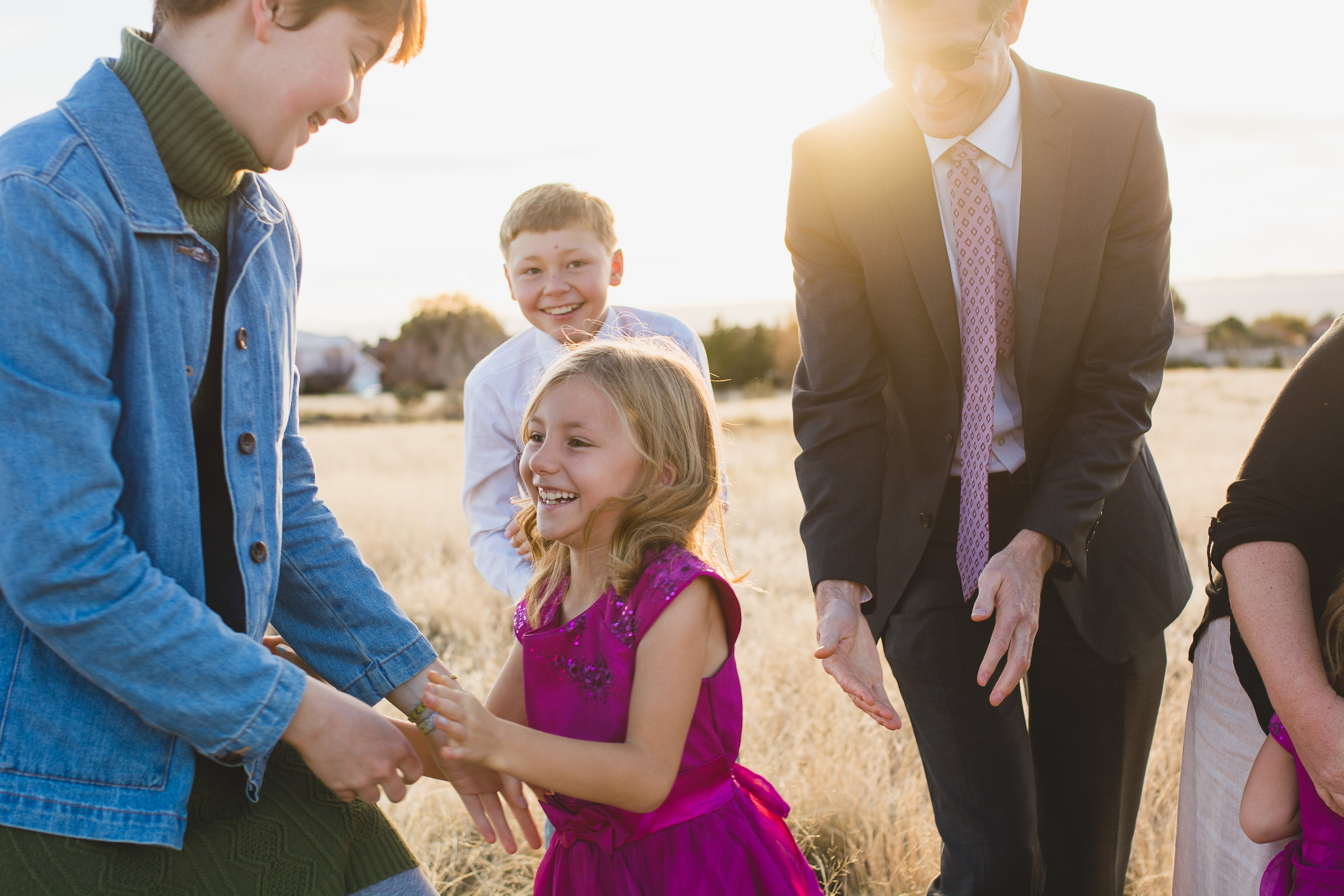 Family caught in the moment of playing with each other in yellow field in Albuquerque