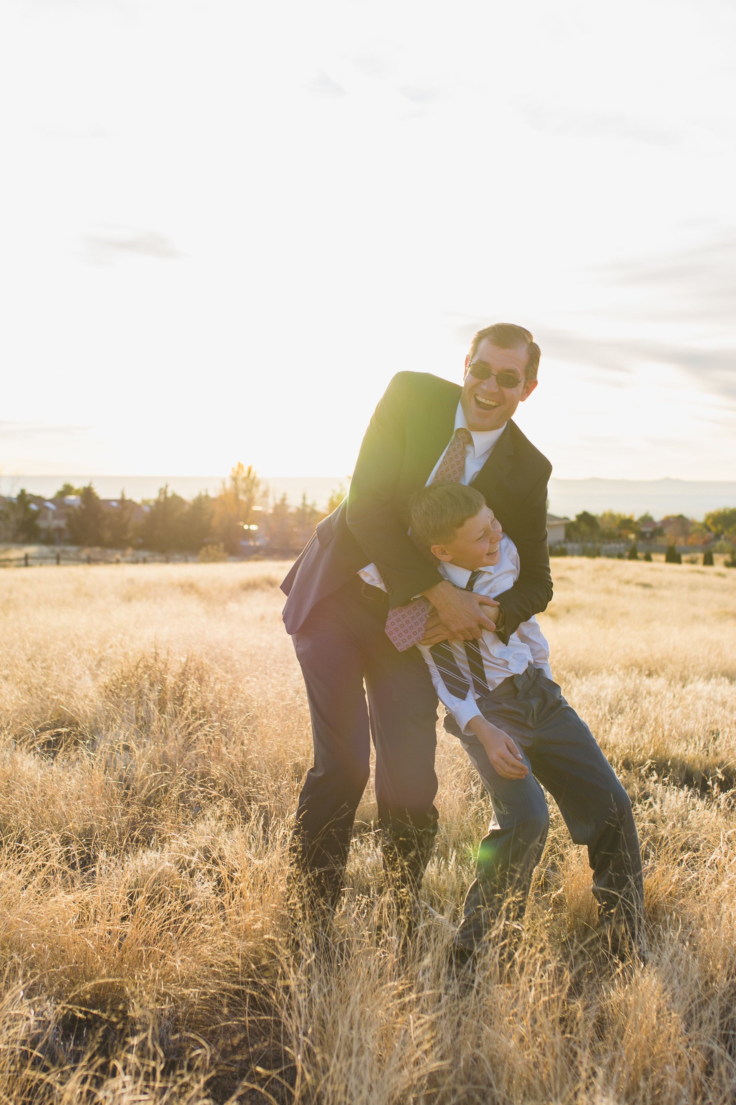 Father hugs and plays with teenage son in yellow field in Albuquerque