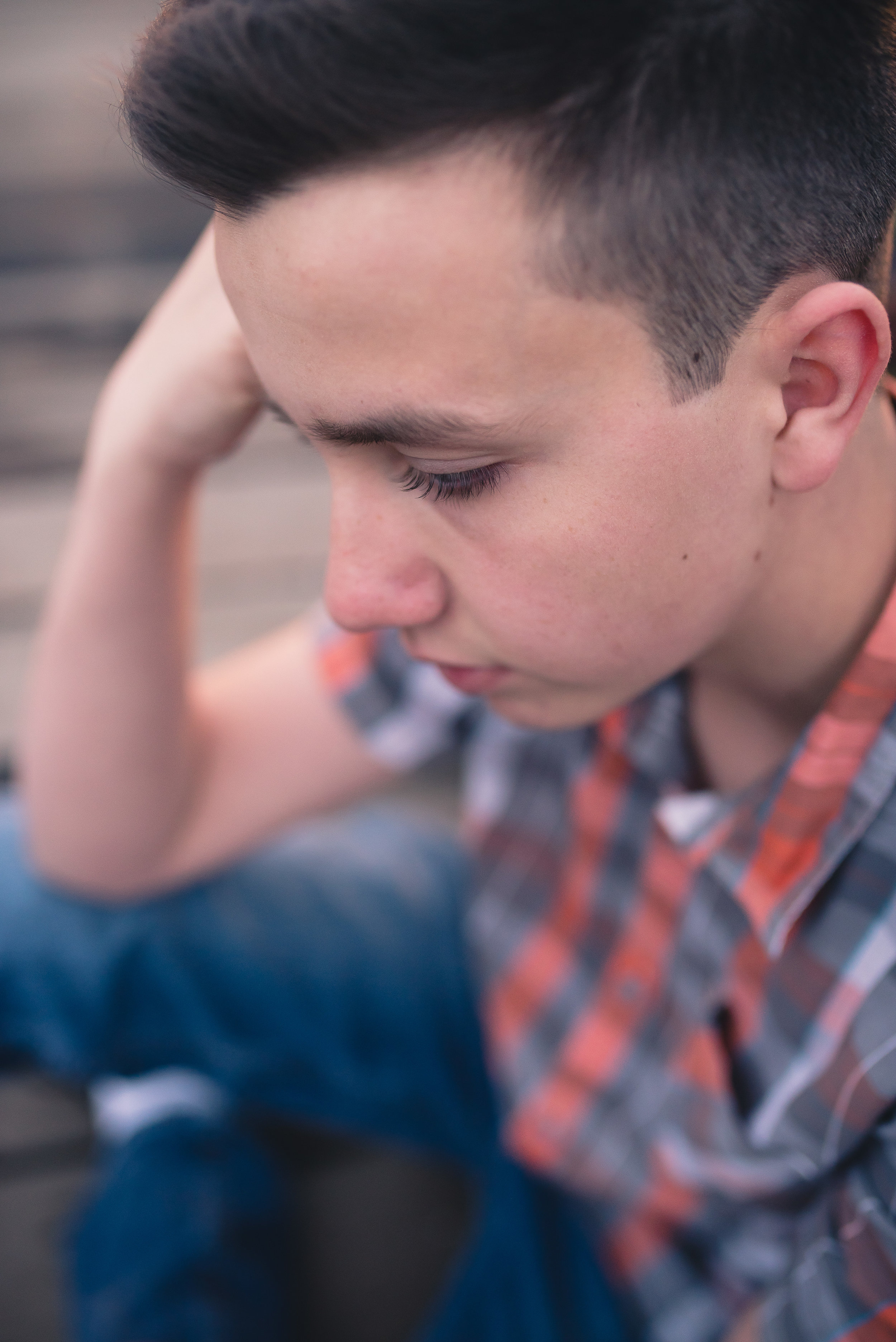 Senior boy looking down while sitting on bridge in Albuquerque