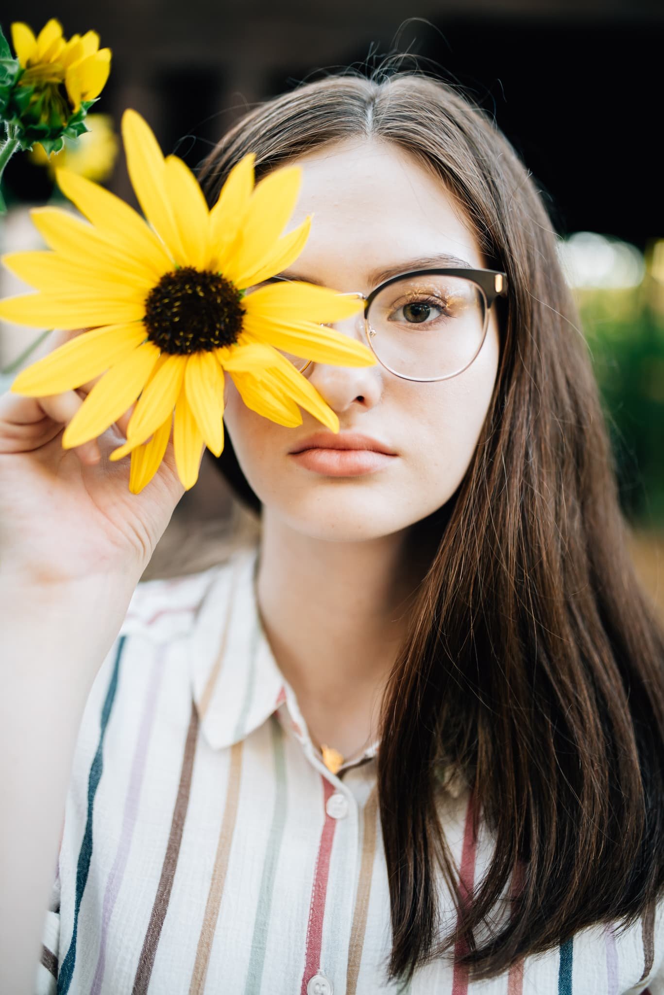 High school senior holding sunflower in front of eye