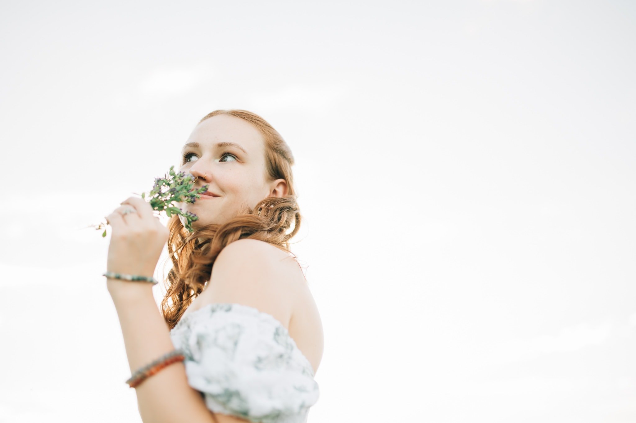 Senior girl holding small bunch of flowers to nose