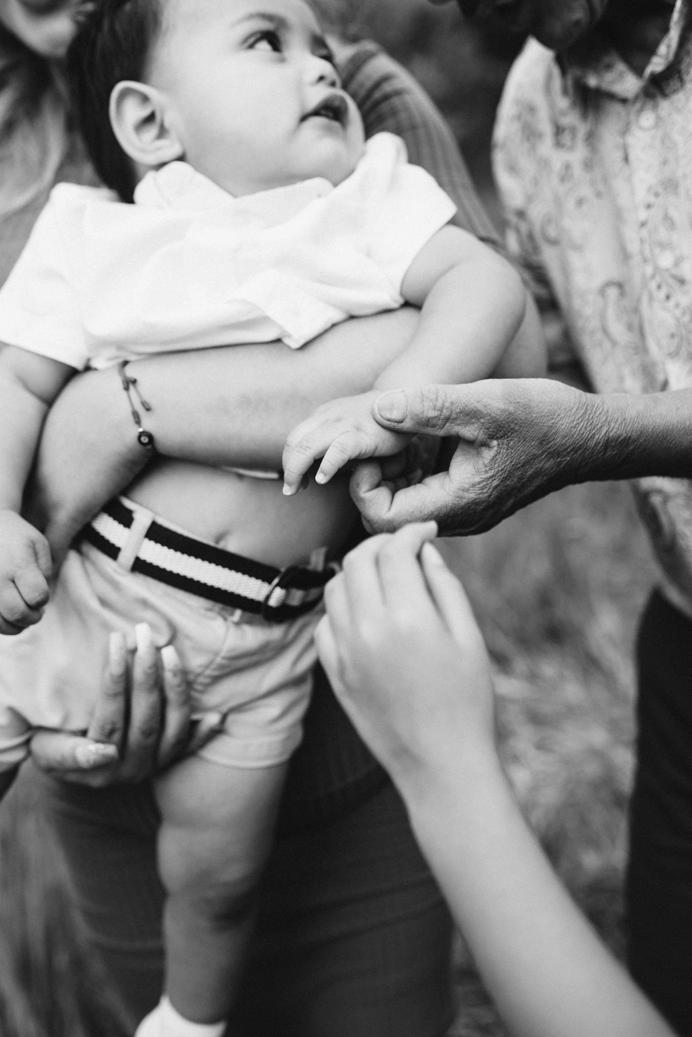 Multiple hands reaching for baby