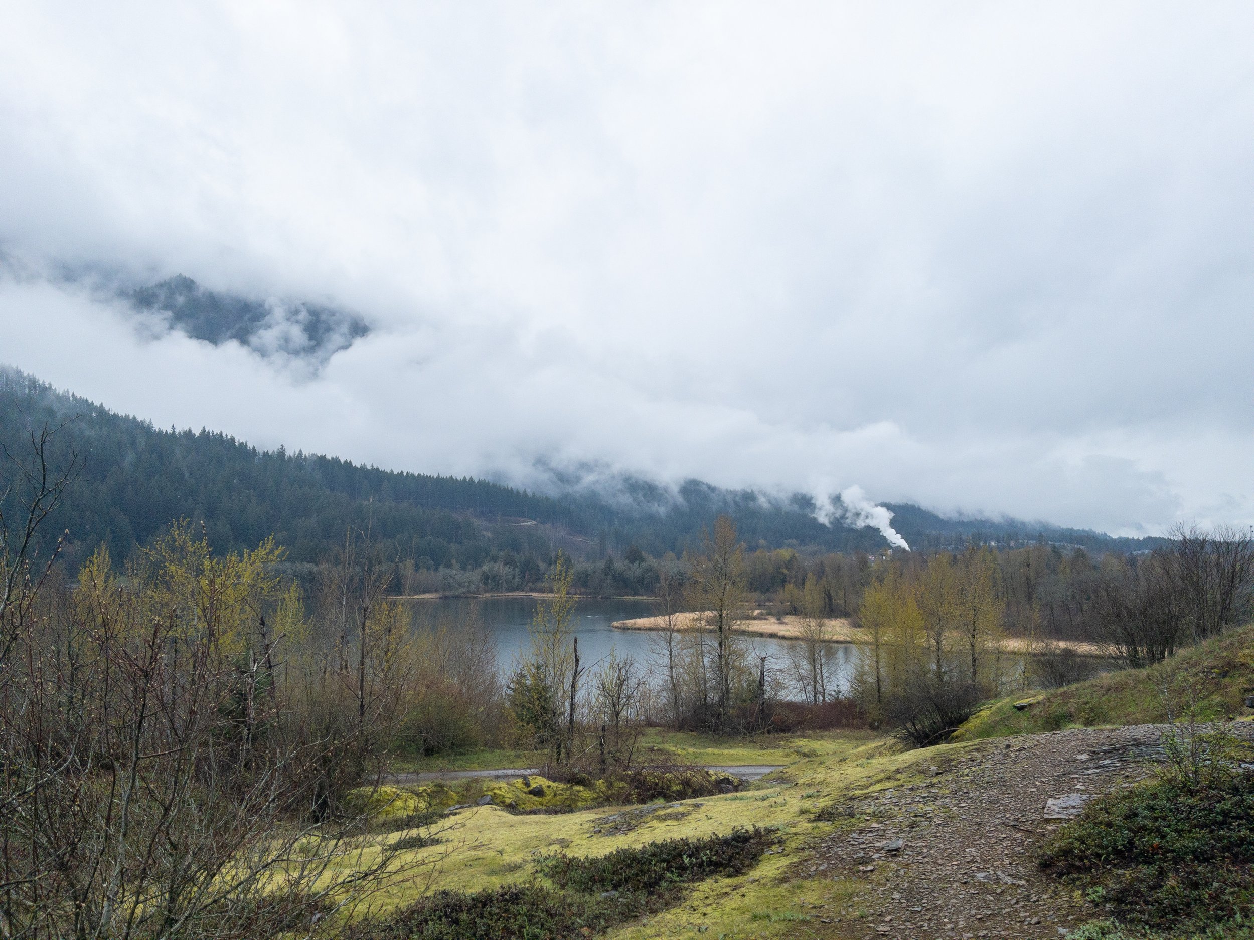 Fog rolling over mountains with a lake at its base in Columbia River Gorge