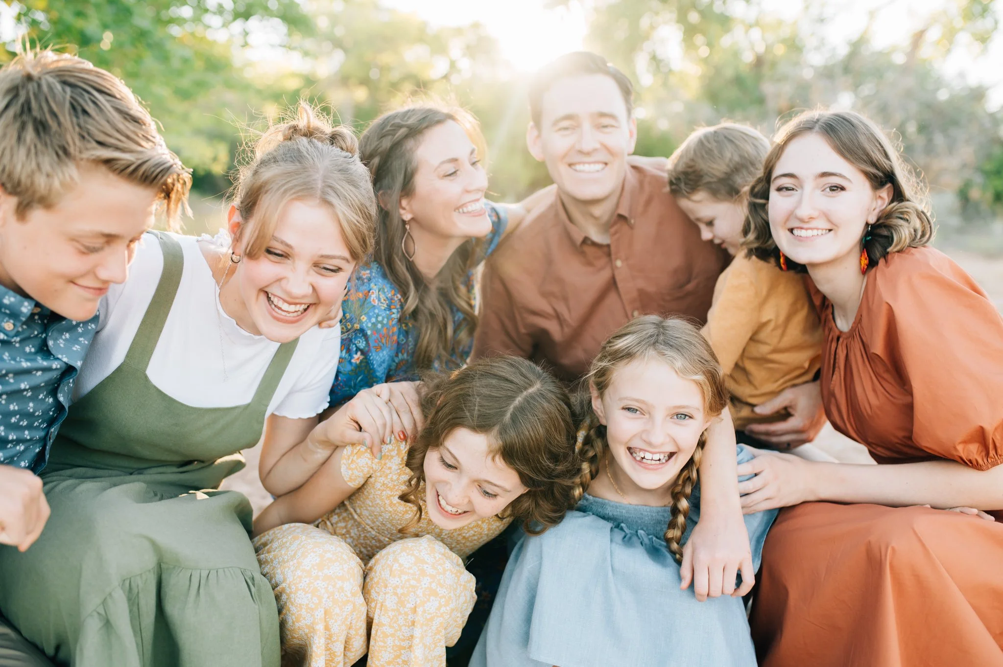 Family with six kids crouching and leaning towards each other while laughing