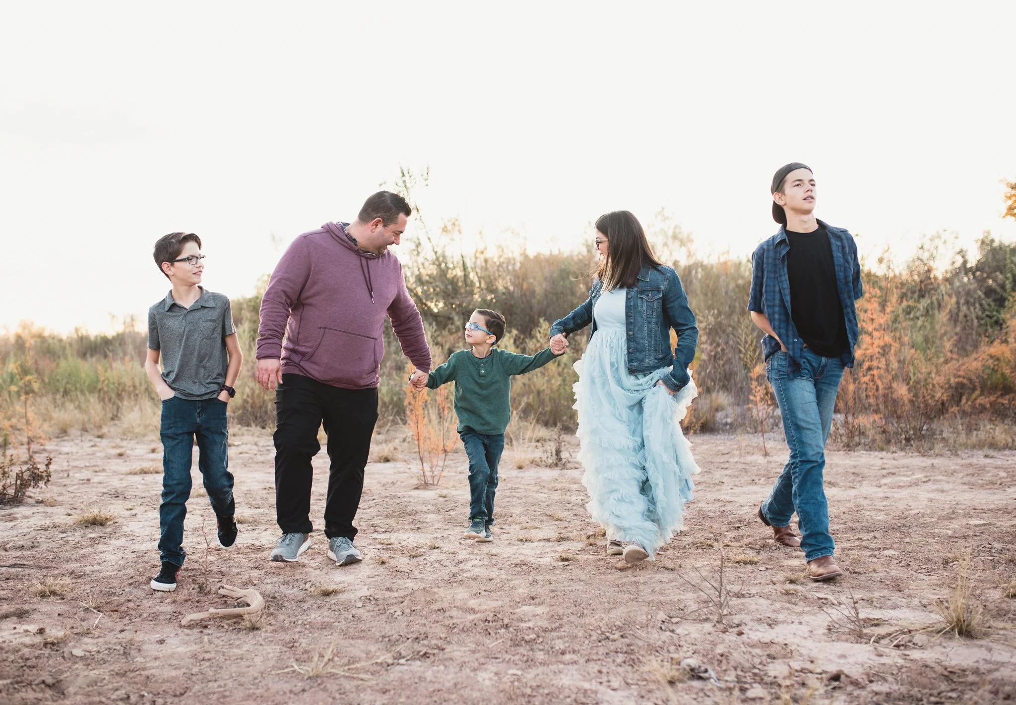 Family with three boys holding hands and walking together