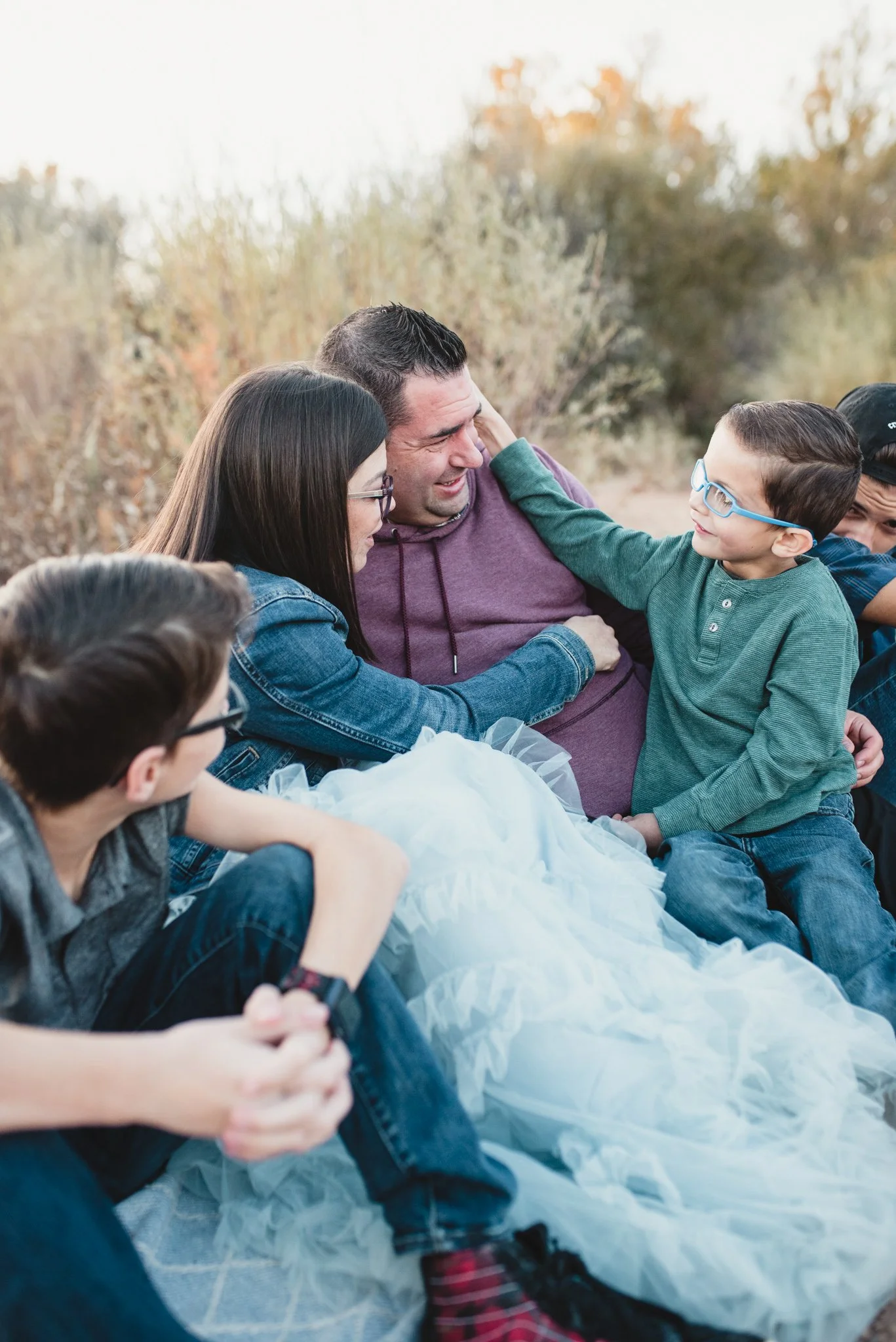 Family with three boys sitting, youngest son reach for dad's face