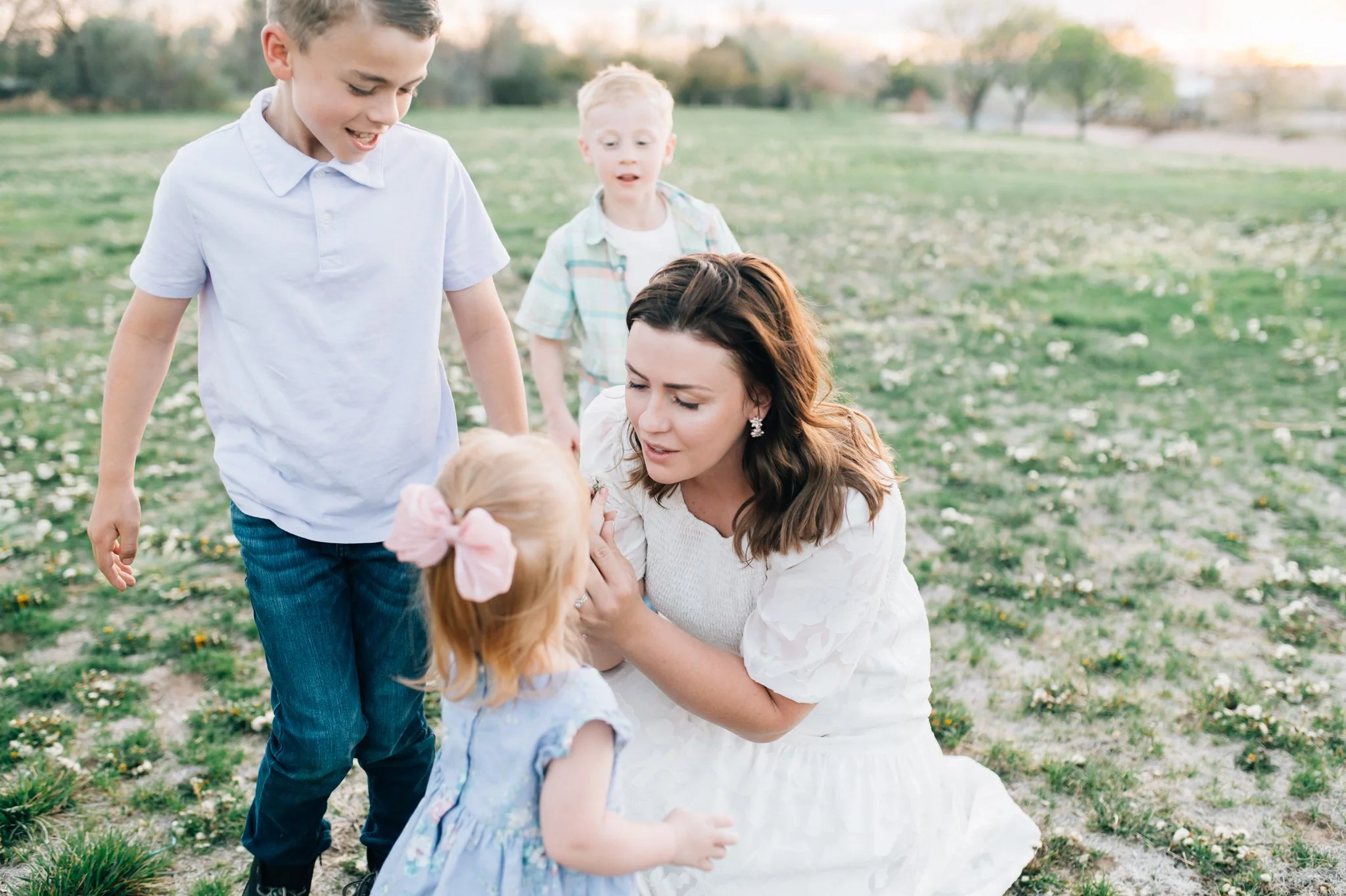 Mom reaching for daughters face as her two sons come up from behind