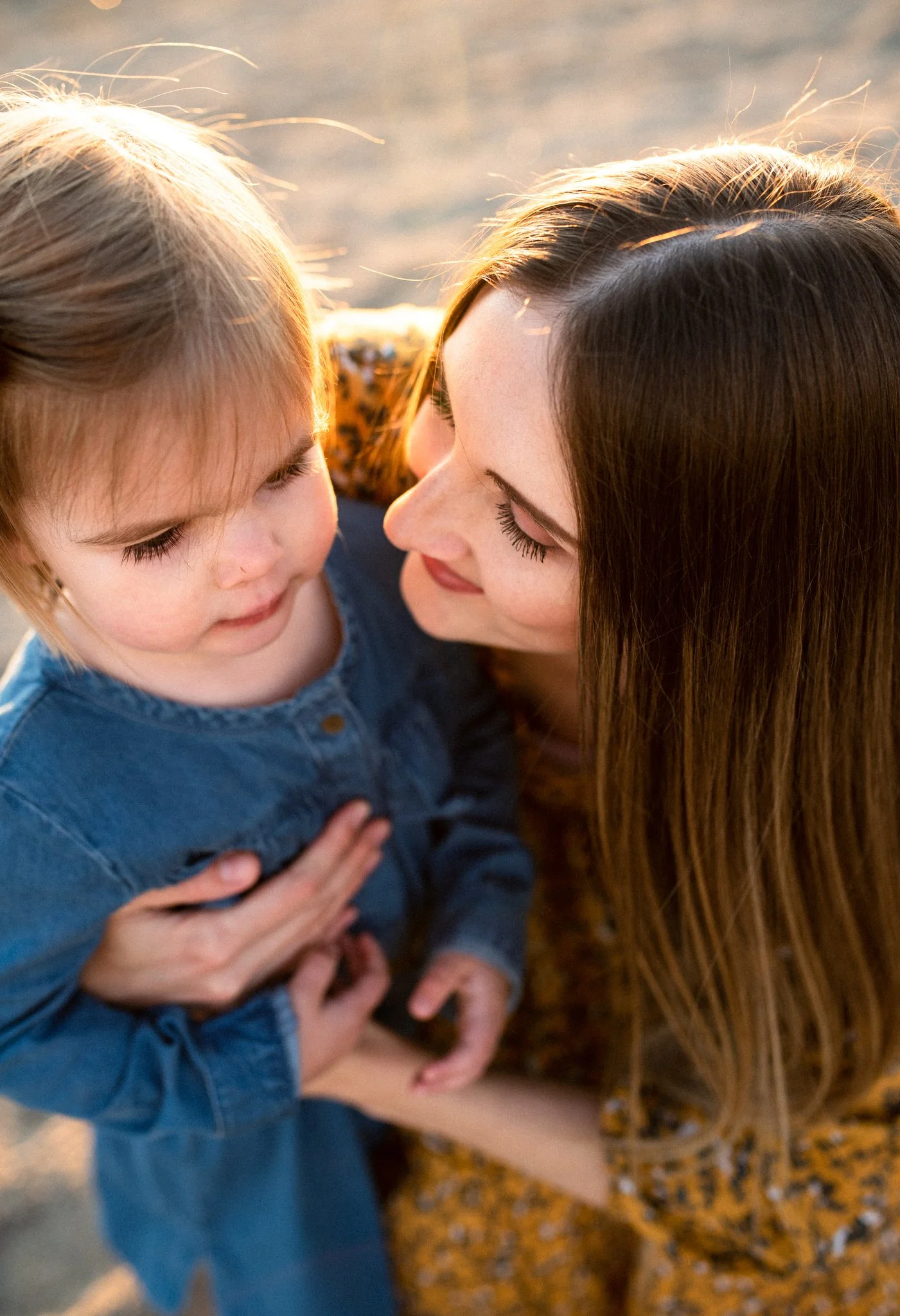 Mom crouching to hug little girl