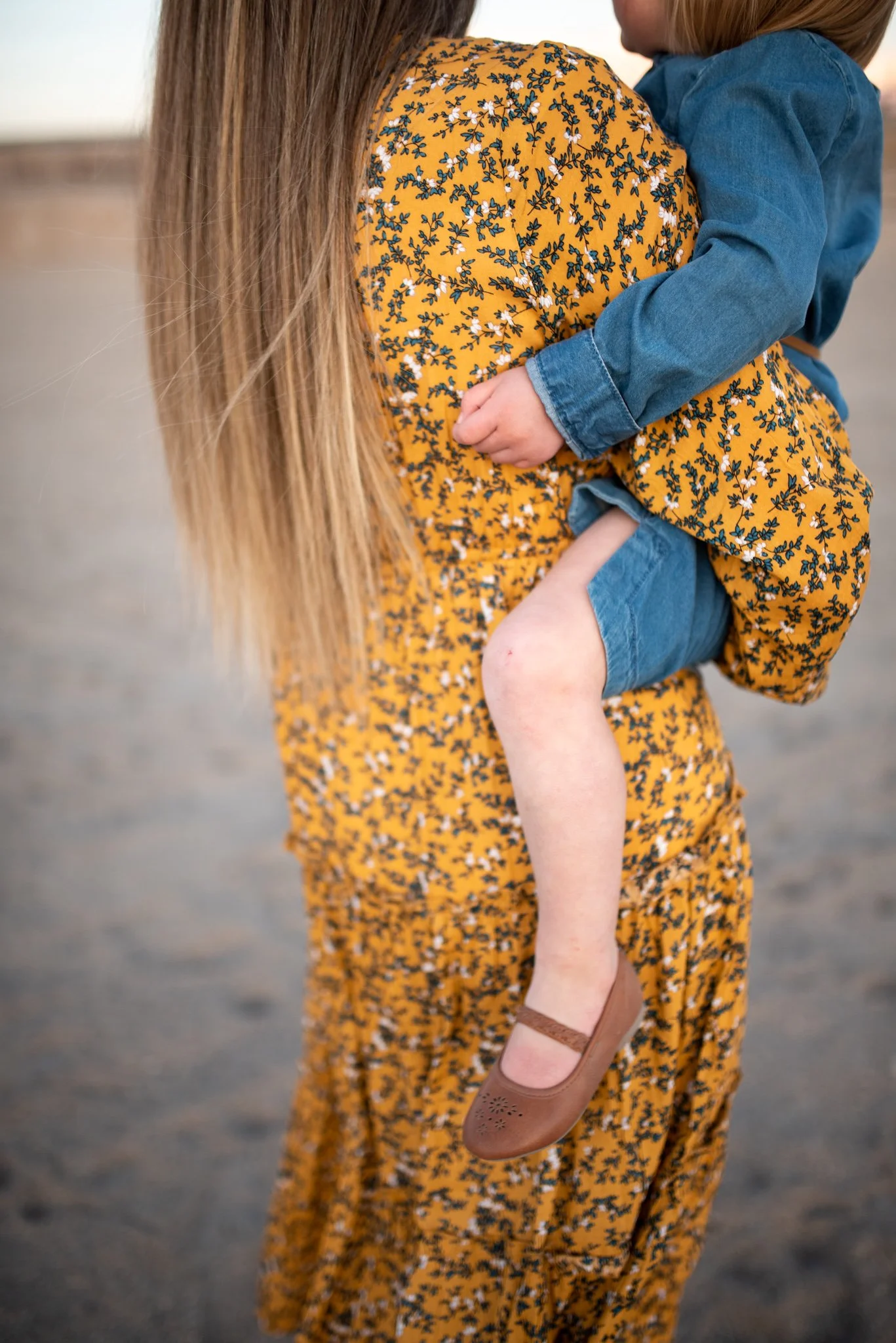 Detail of Mom carrying her little girl with her daughter's hands holding on to her