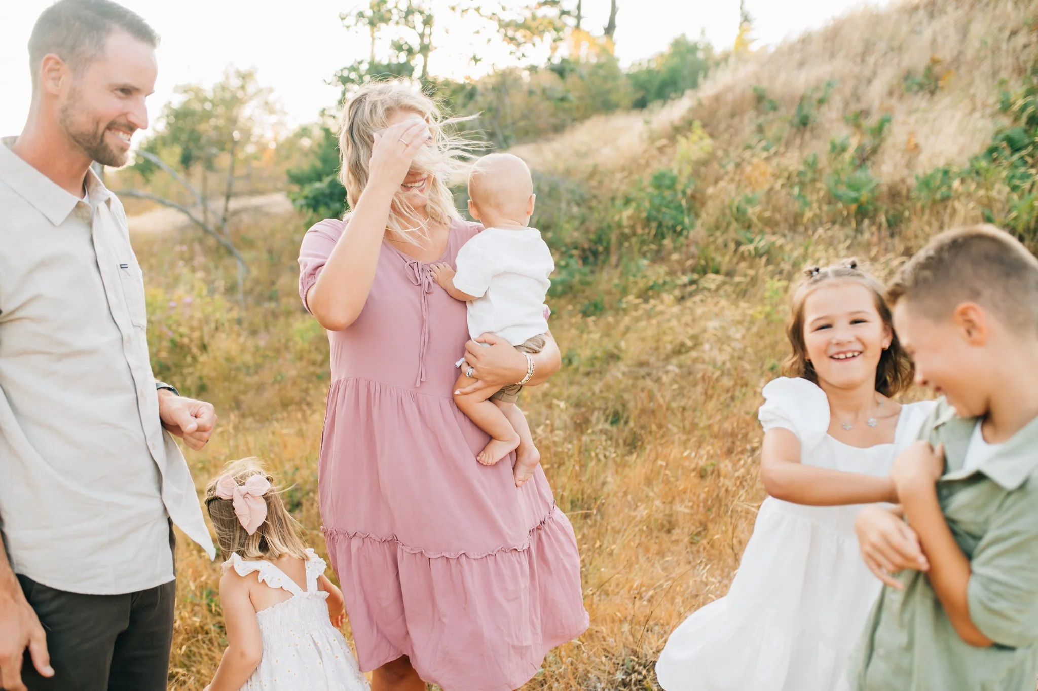 Family with four kids, parents watch as oldest two tickle each other
