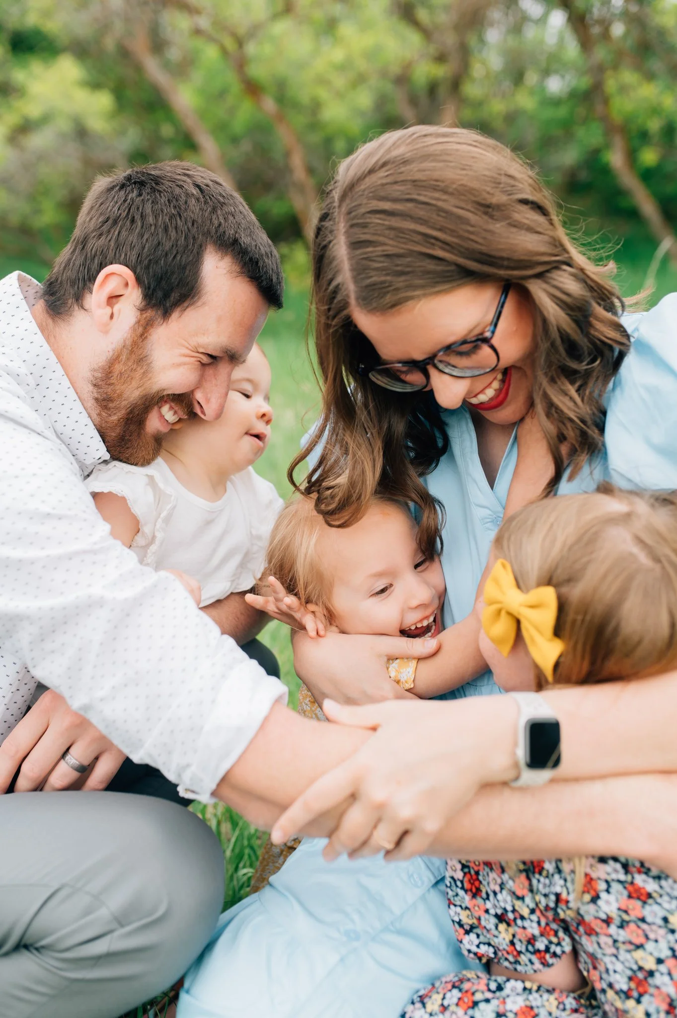 Family with three young daughters sitting and hugging