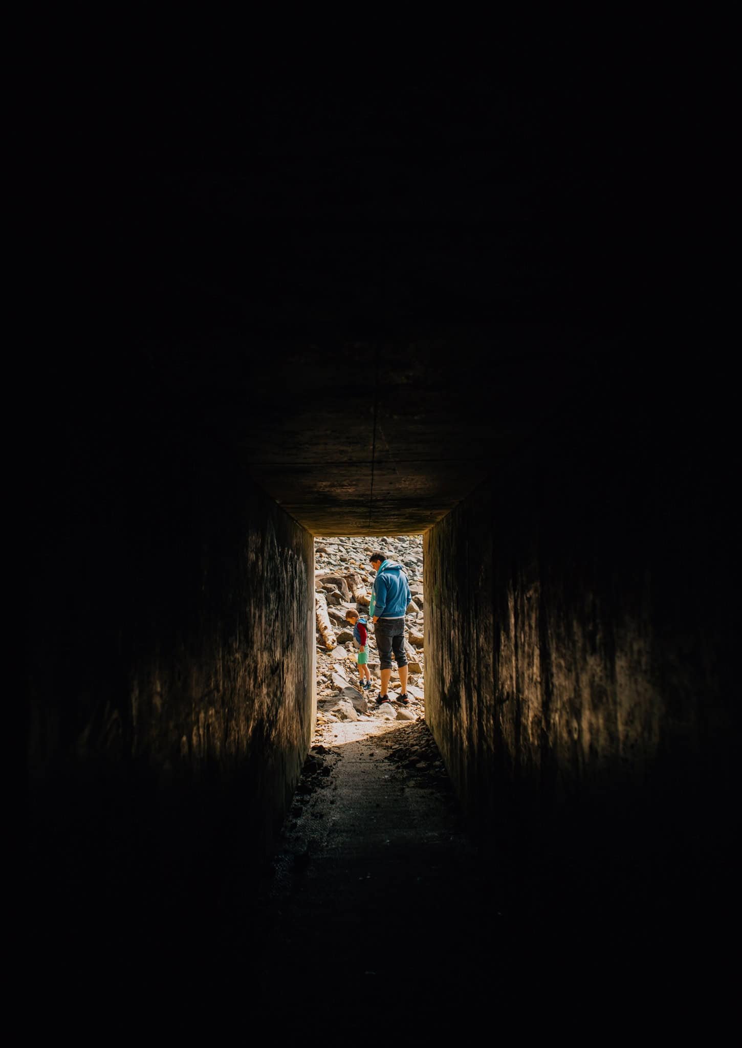 a tunnel with a small opening showing a dad and son at Tunnel Beach, OR
