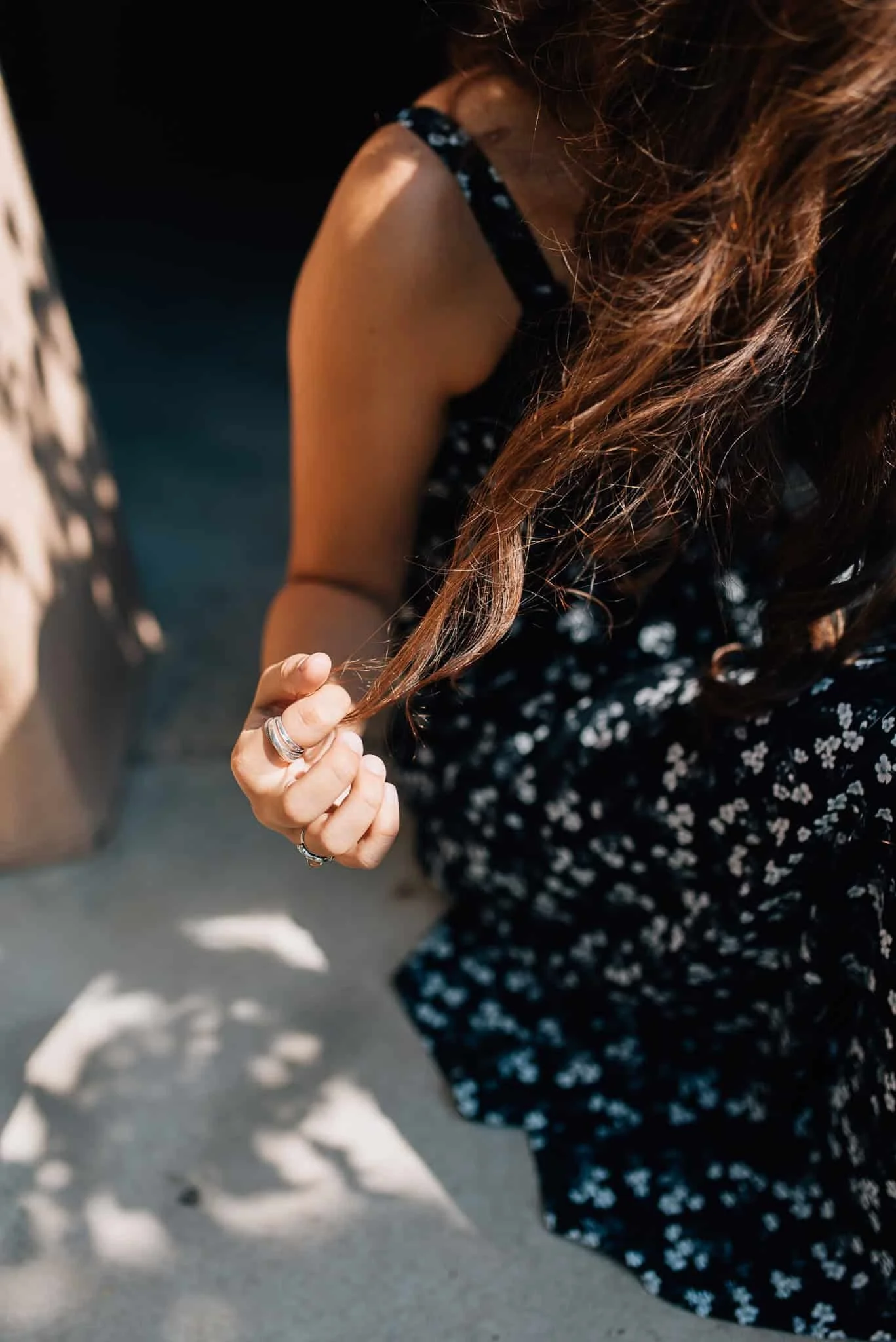 close up of senior girl's hand as she twirls her hair with dappled shadows