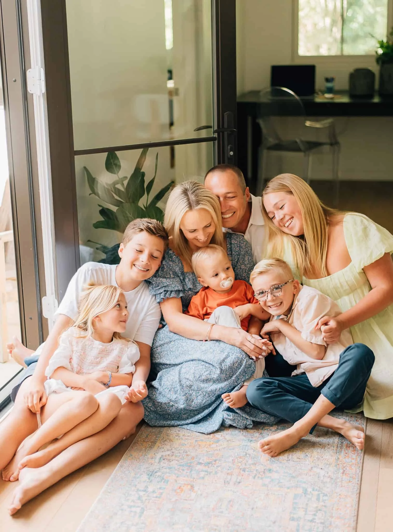 family with five kids sits down and snuggles together