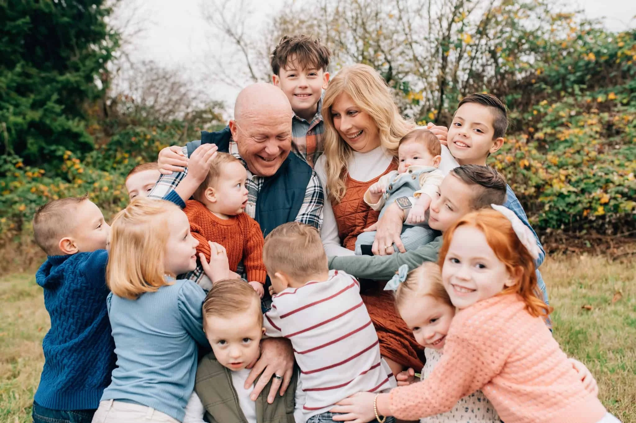 Grandparents in the middle of all their grandkids while they all try to hug them