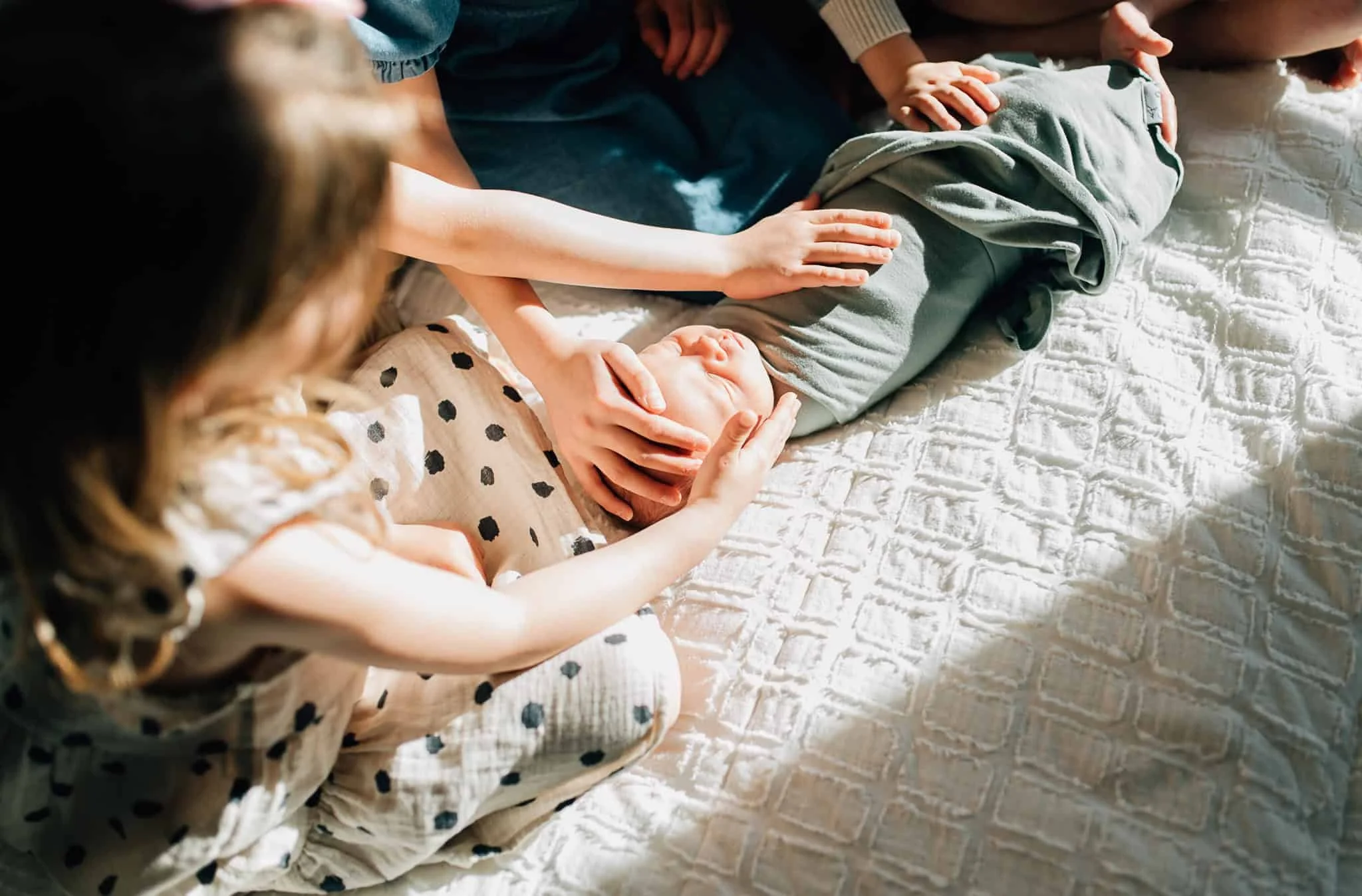 shaft of light lights up newborn baby surrounded by siblings