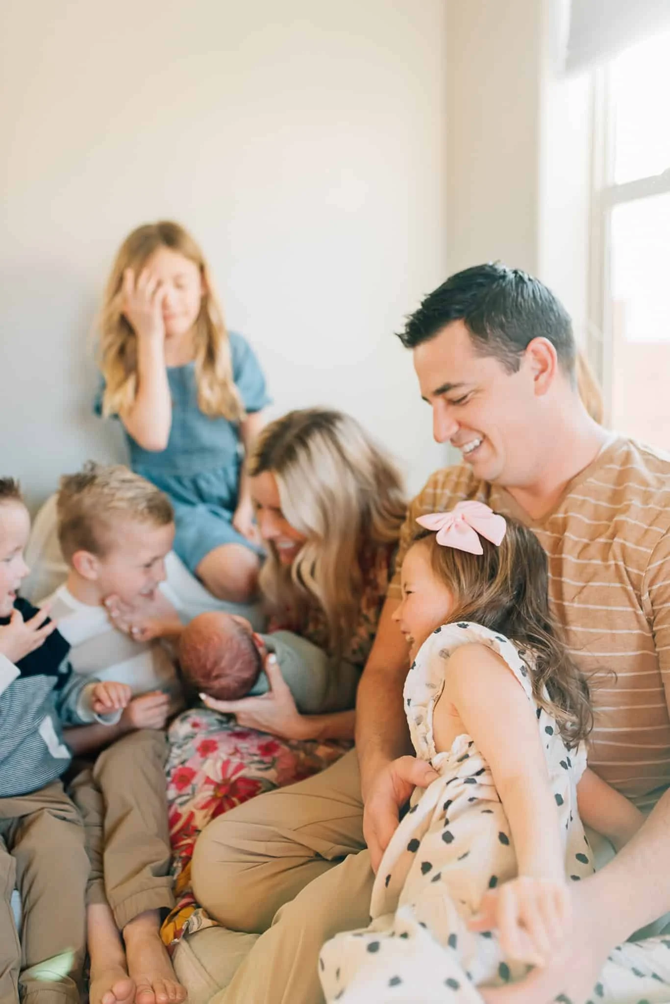 Family with six kids sits on couch and laugh and interact