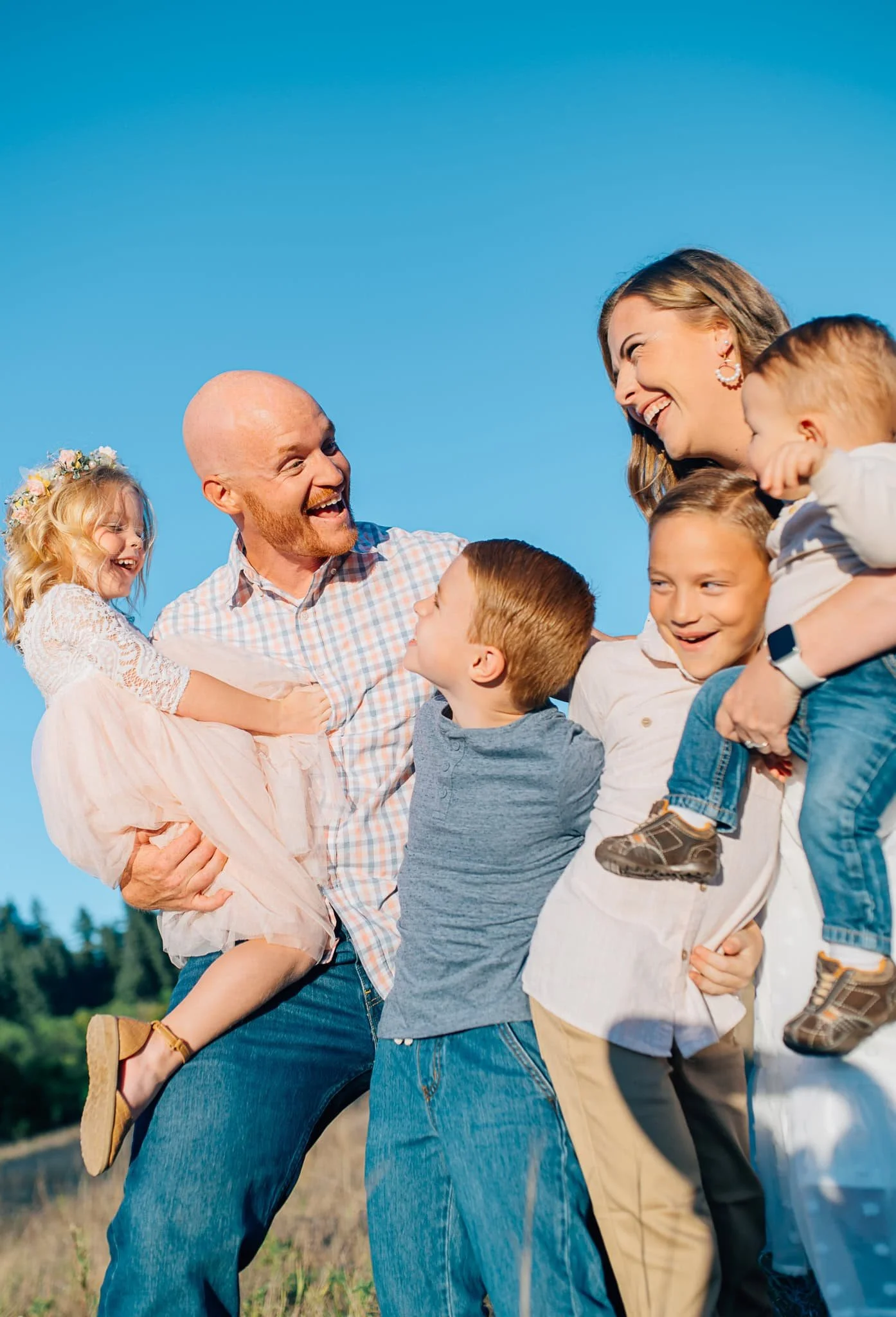 Family close together and laughing at something with bright blue sky behind them