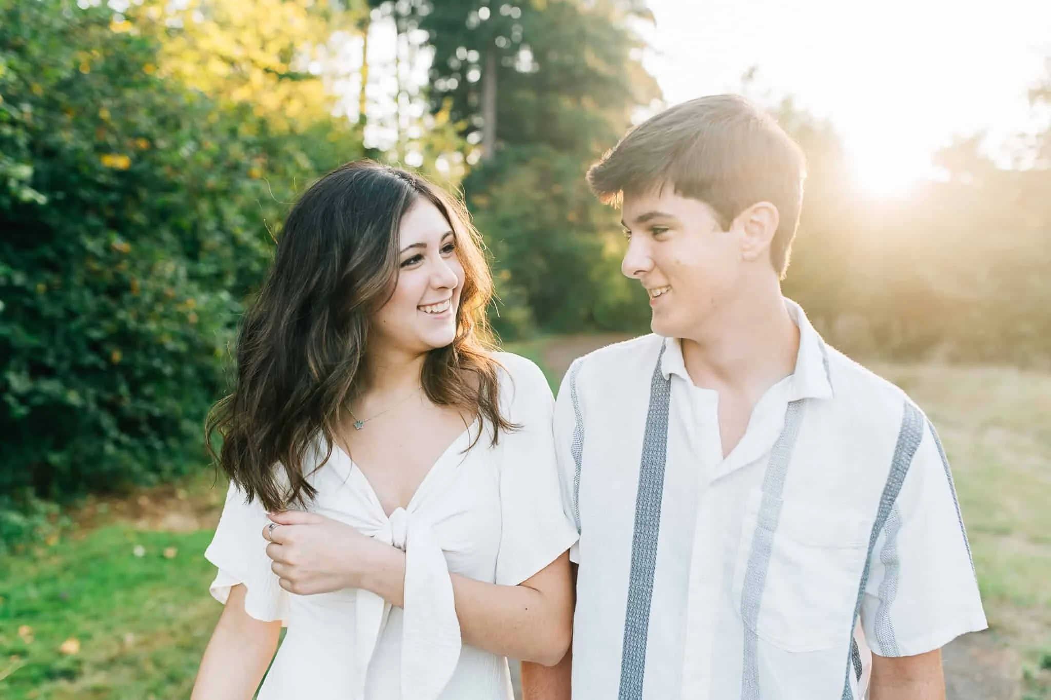 teenage brother and sister look at each and smile with green foliage behind them at Hockinson Park in Vancouver WA