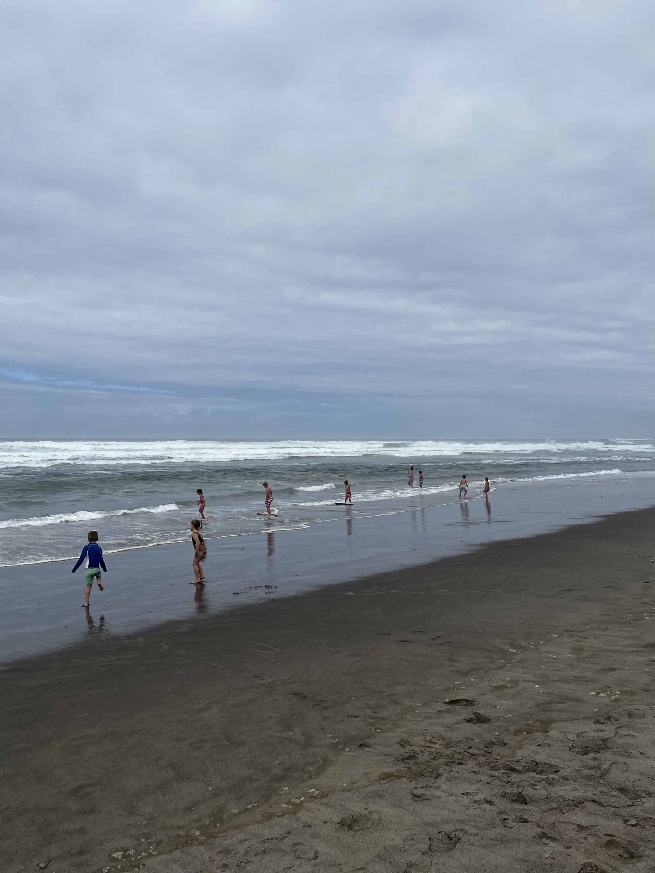 Far away shot of kids playing at Neskowin beach on a cloudy day