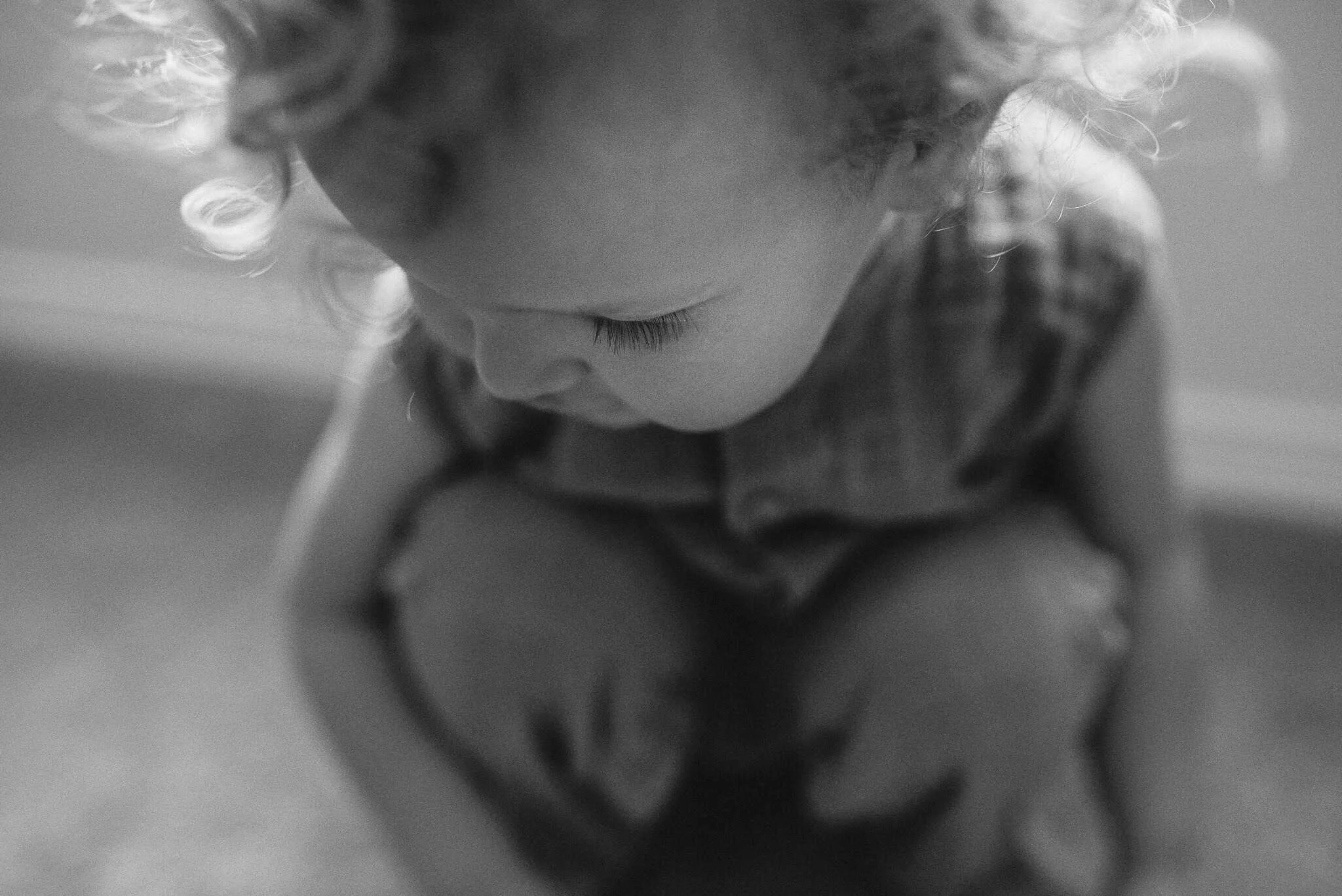 little boy with curly hair looks down, his curls are lit by back light