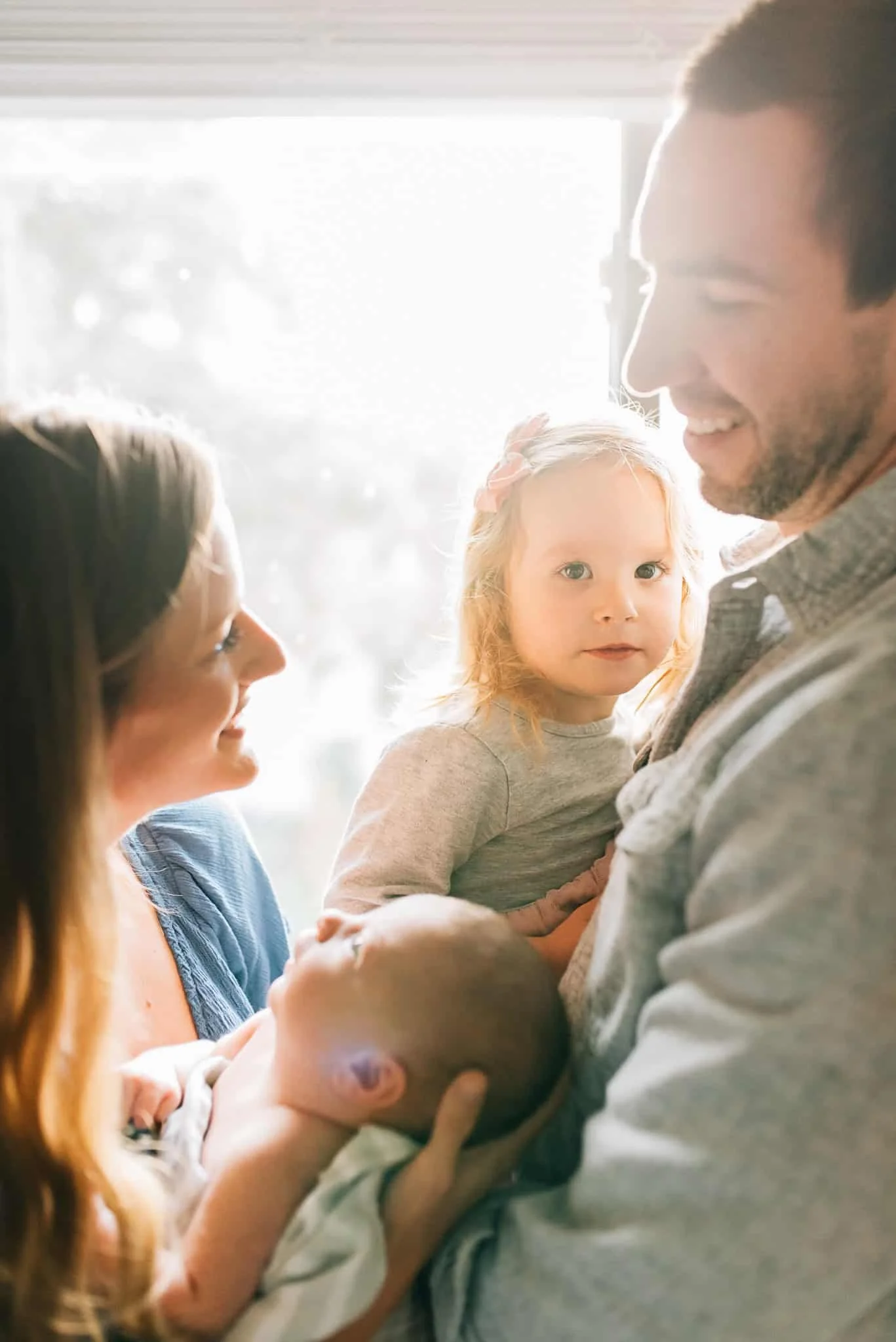 mom holds newborn baby while dad holds older sister