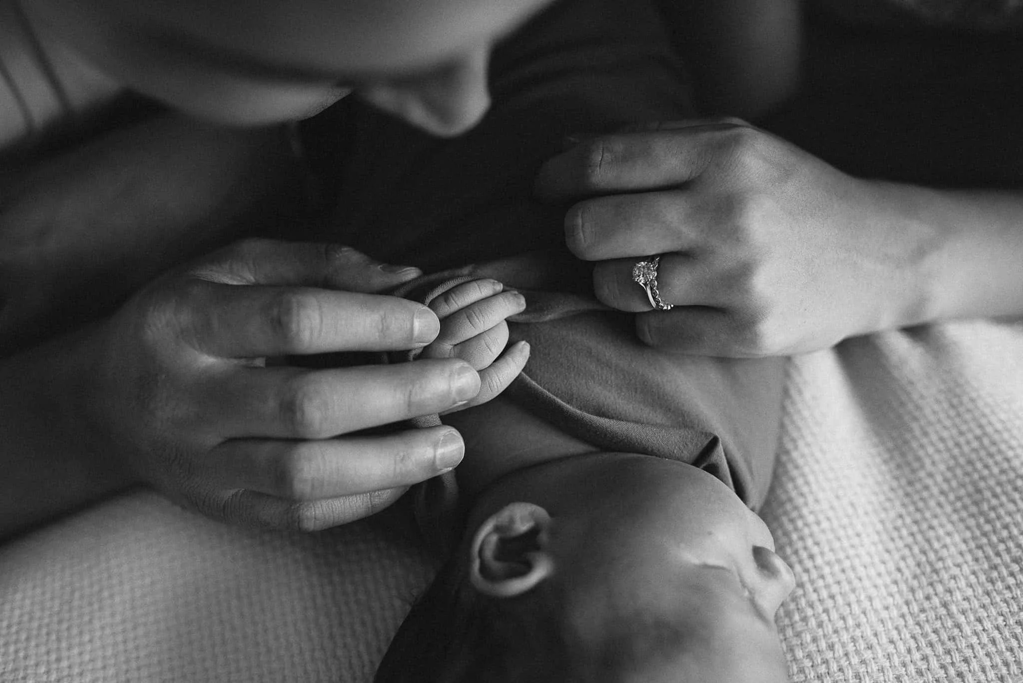 close-up of parents holding newborn baby's hand
