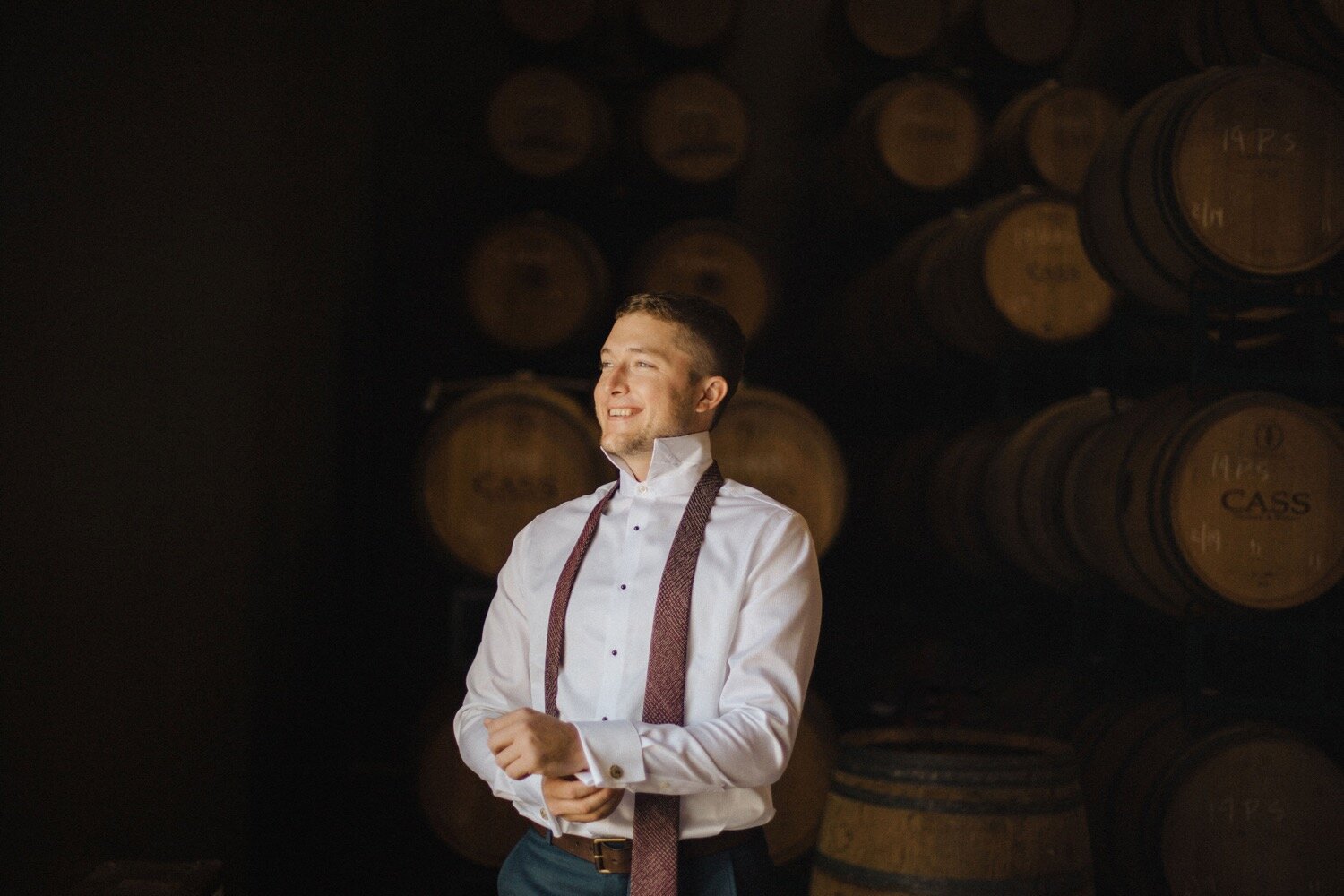 Groom gets ready for his wedding in the Barrel Room at Cass Winery. SLO Wedding Photographer