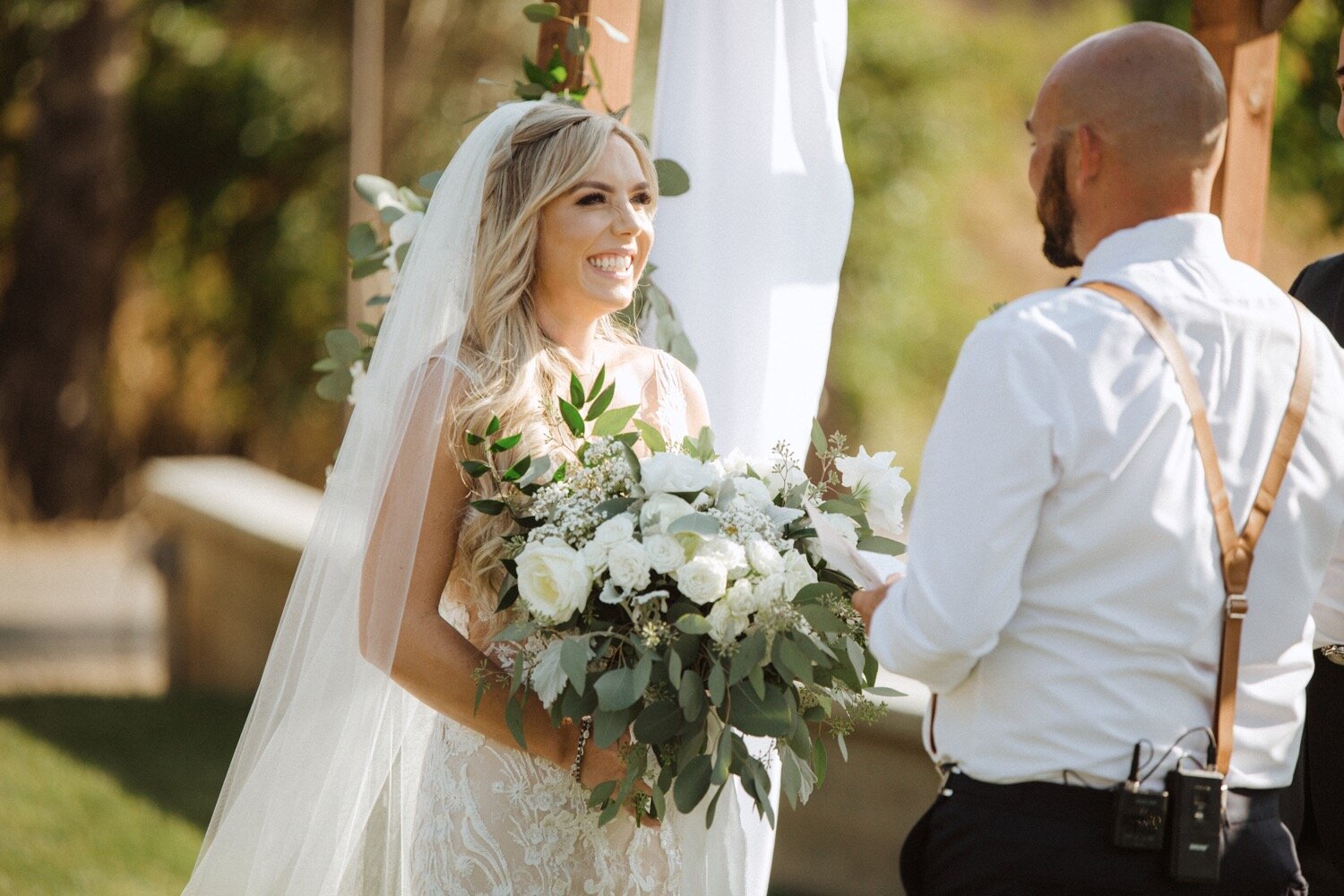 groom reads vows to his bride as she smiles at him at their higuera ranch wedding. california wedding photographer