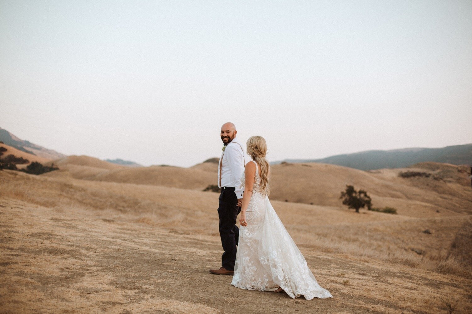 bride and groom walk through the rolling hills during their higuera ranch wedding. slo wedding photographer