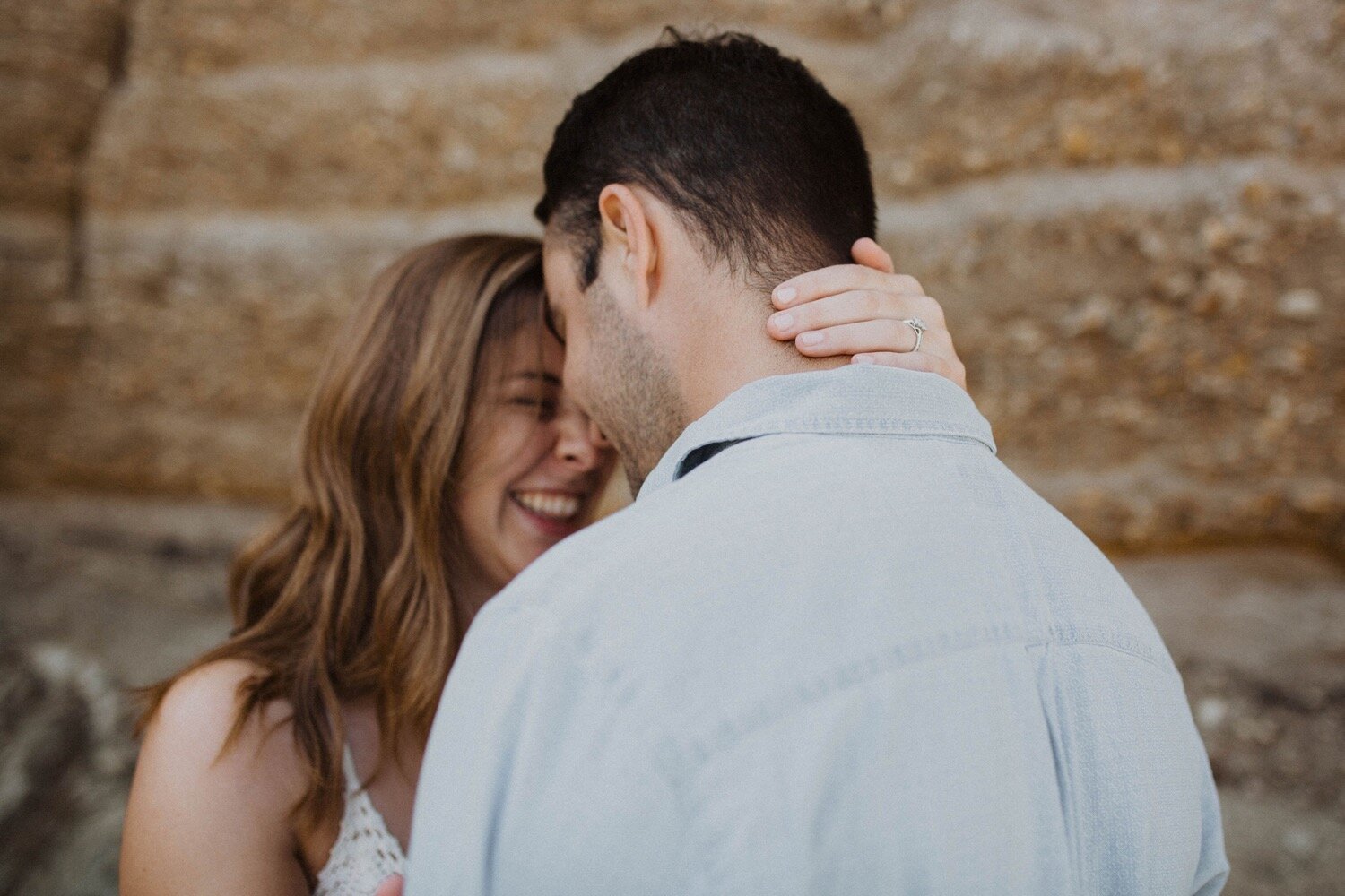 couple laughs with their heads together as the bride shows off her engagement ring during their engagement session at montana de oro. san luis obispo proposal photographer