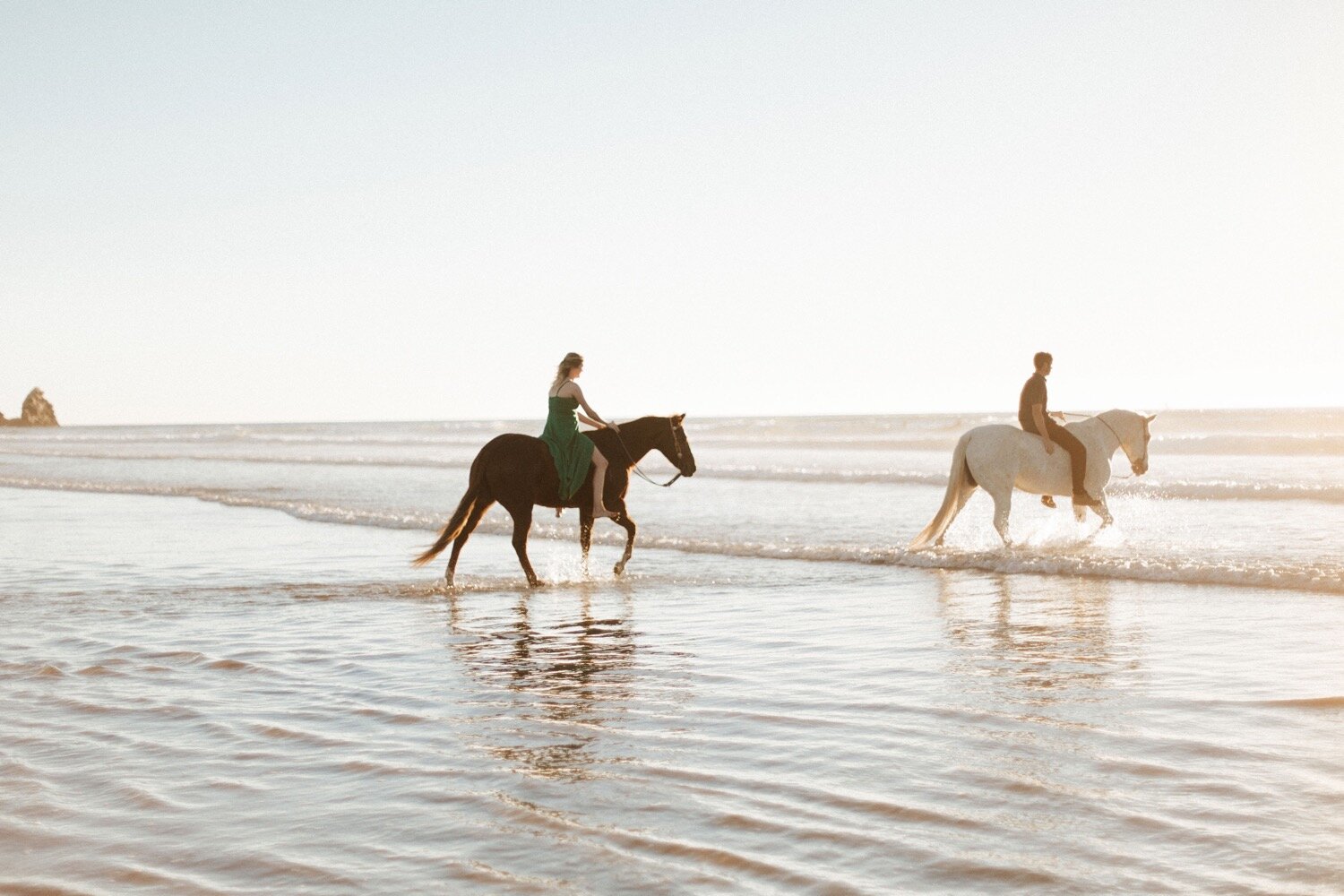 couple rides their horses into the ocean at morro bay beach, captured by slo photographer poppy and vine