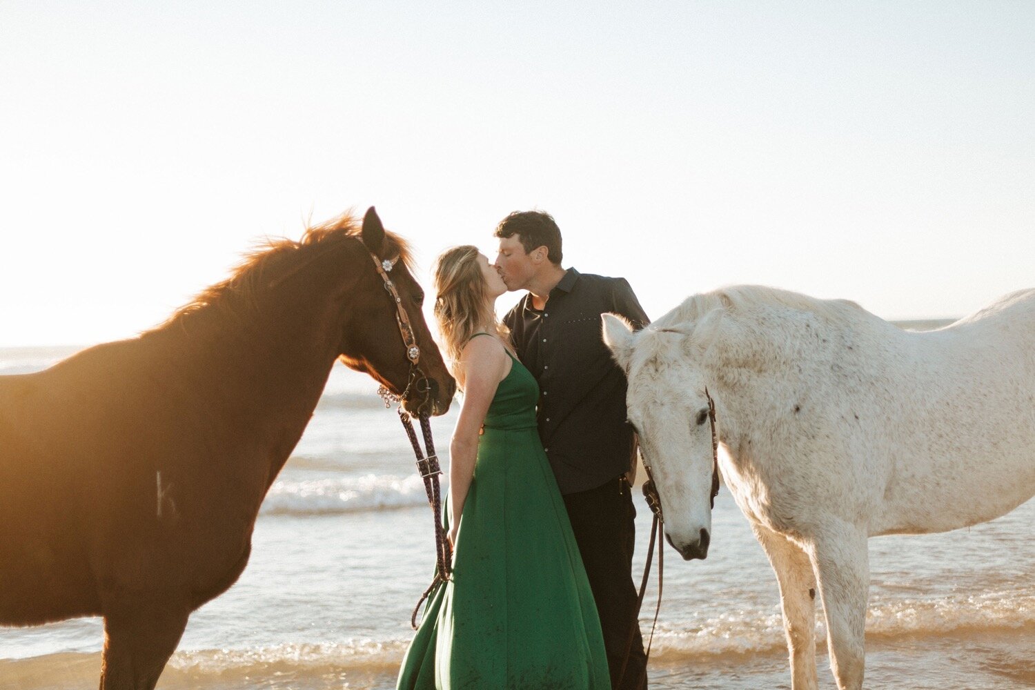 couple kisses during their morro bay engagement photoshoot with their horses, captured by slo engagement photographer poppy and vine