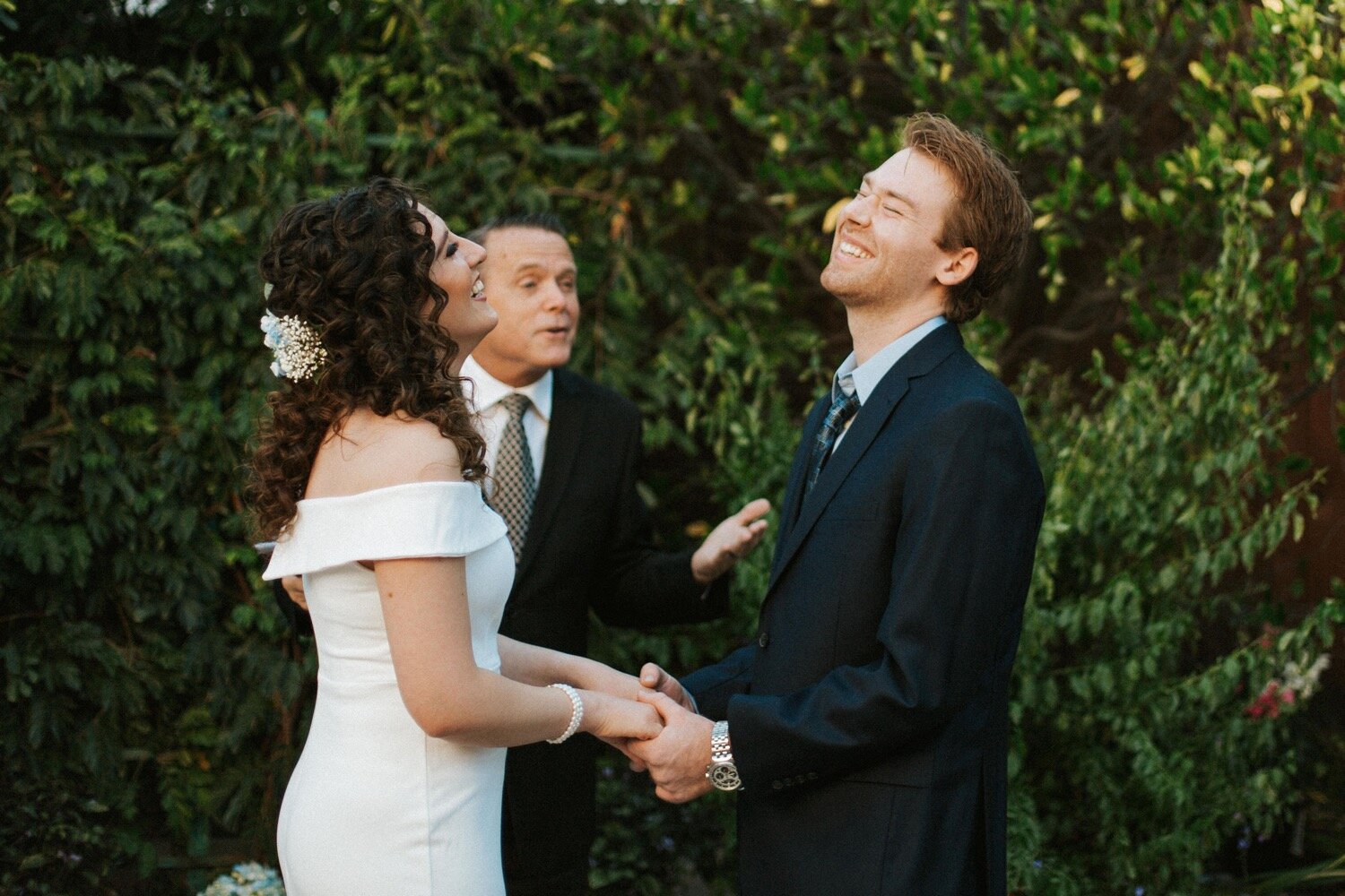  bride and groom laugh in the middle of their intimate backyard elopement in Los Angeles. SLO wedding photography duo Poppy and Vine was on scene to capture every moment 