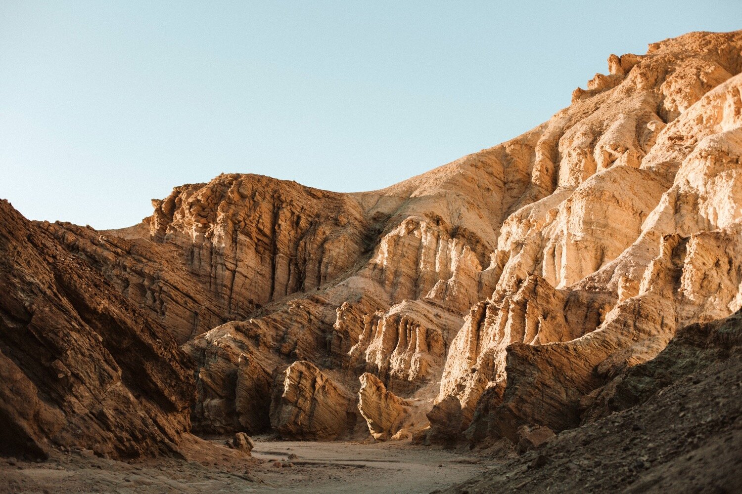 the jagged cliffs of golden canyon in death valley national park soak in the last light of a winter sunset, captured by california elopement photographer poppy and vine