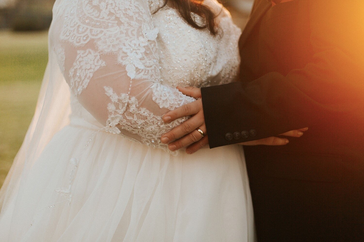  close up photo shows groom holding bride as the golden sun sets behind them at their intimate nipomo wedding, captured by los olivos wedding photographer poppy and vine 
