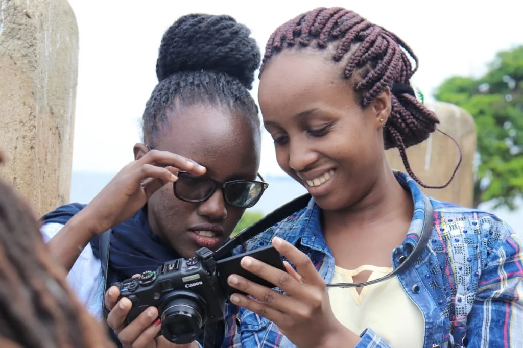 Prisca and Diana looking over an image they took at the Youth Arts Movement Camp