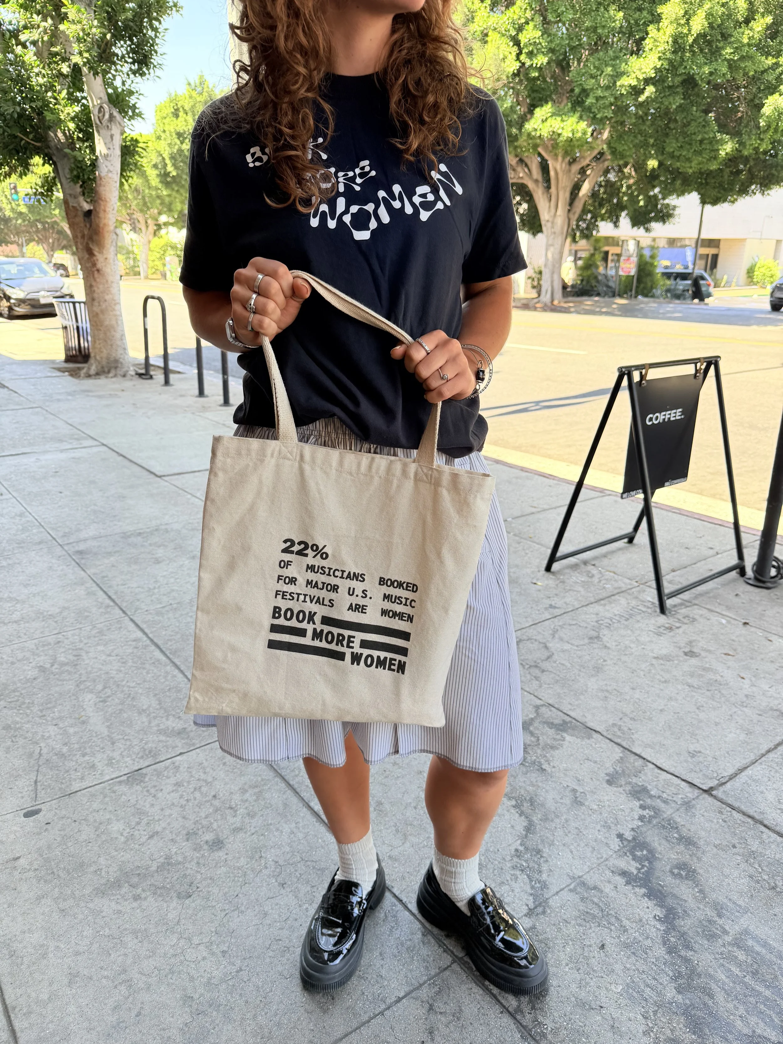 Nico carrying the Book More Women tote bag