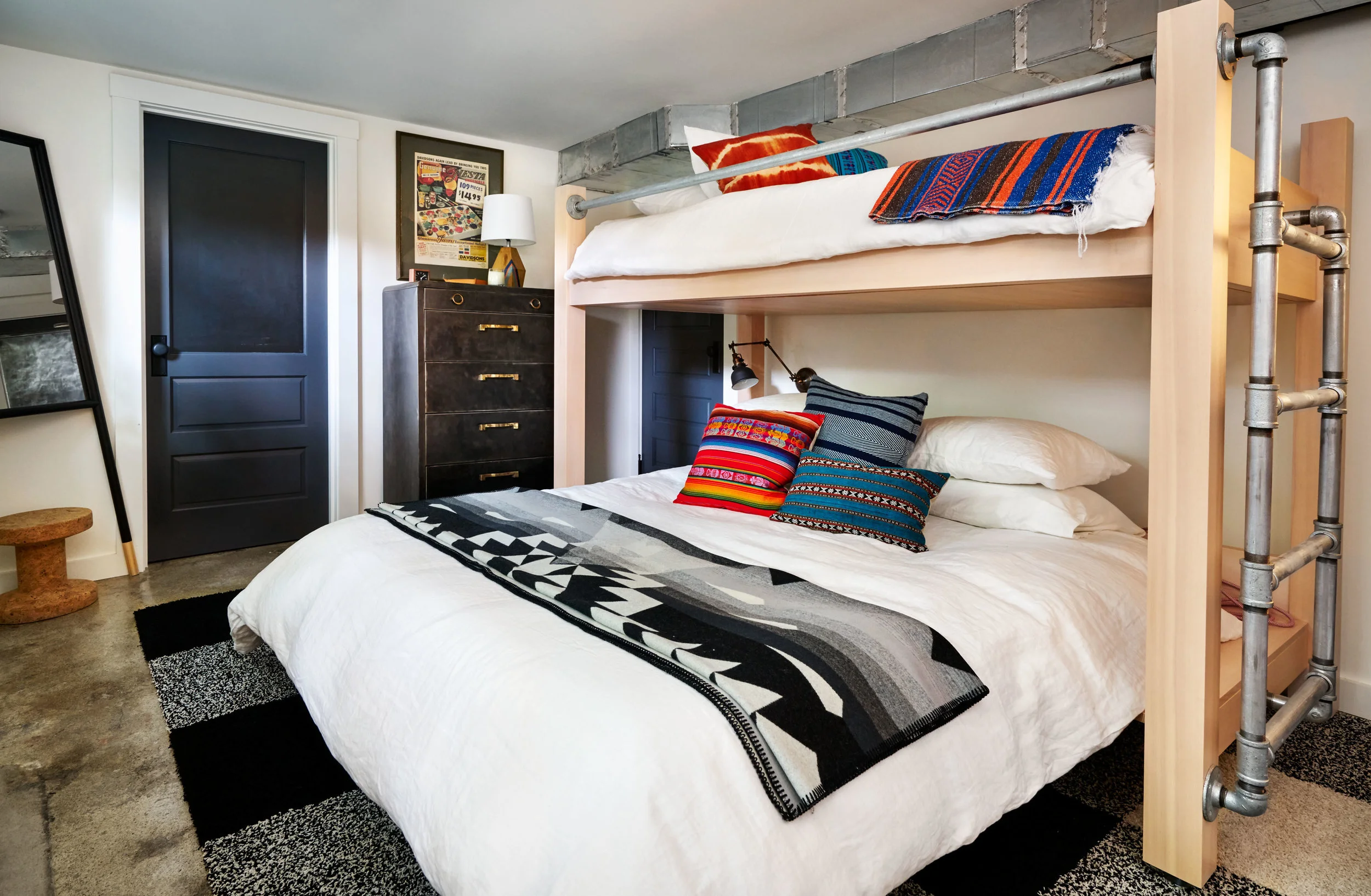 The client wanted as much flexibility in the guest room as possible so we designed a twin over the queen bunk bed using local spruce and plumbing fixtures as accents to tie in with the industrial thread running through this basement conversion.