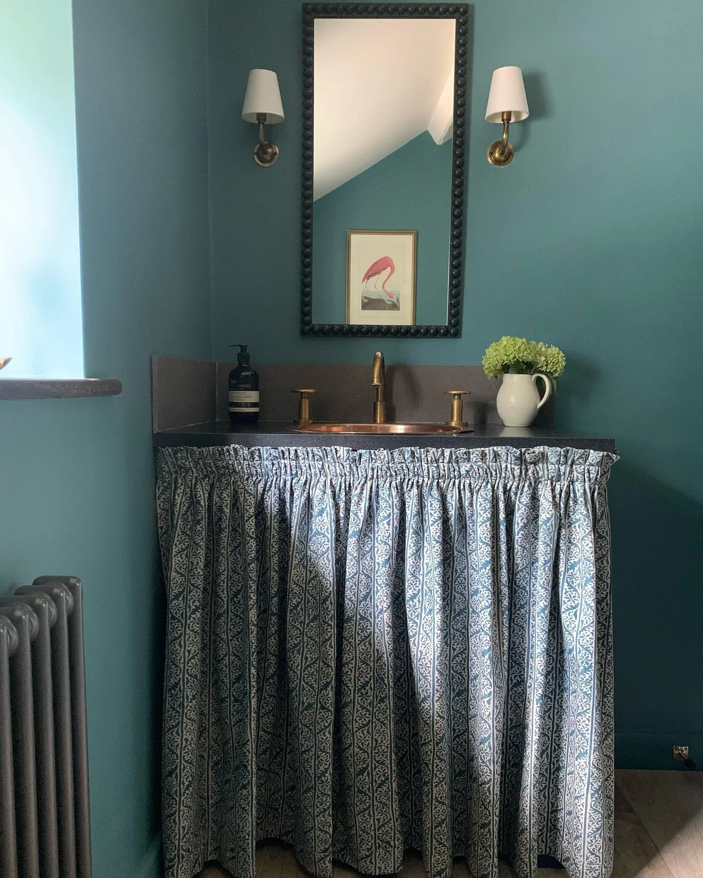 A pretty little vanity skirt we recently installed with curtains that wrap around the side of the vanity.  I think the fabric plays with the light to soften the room. The bespoke slim mirror we painted in Hague Blue with a waxed finish and we happily