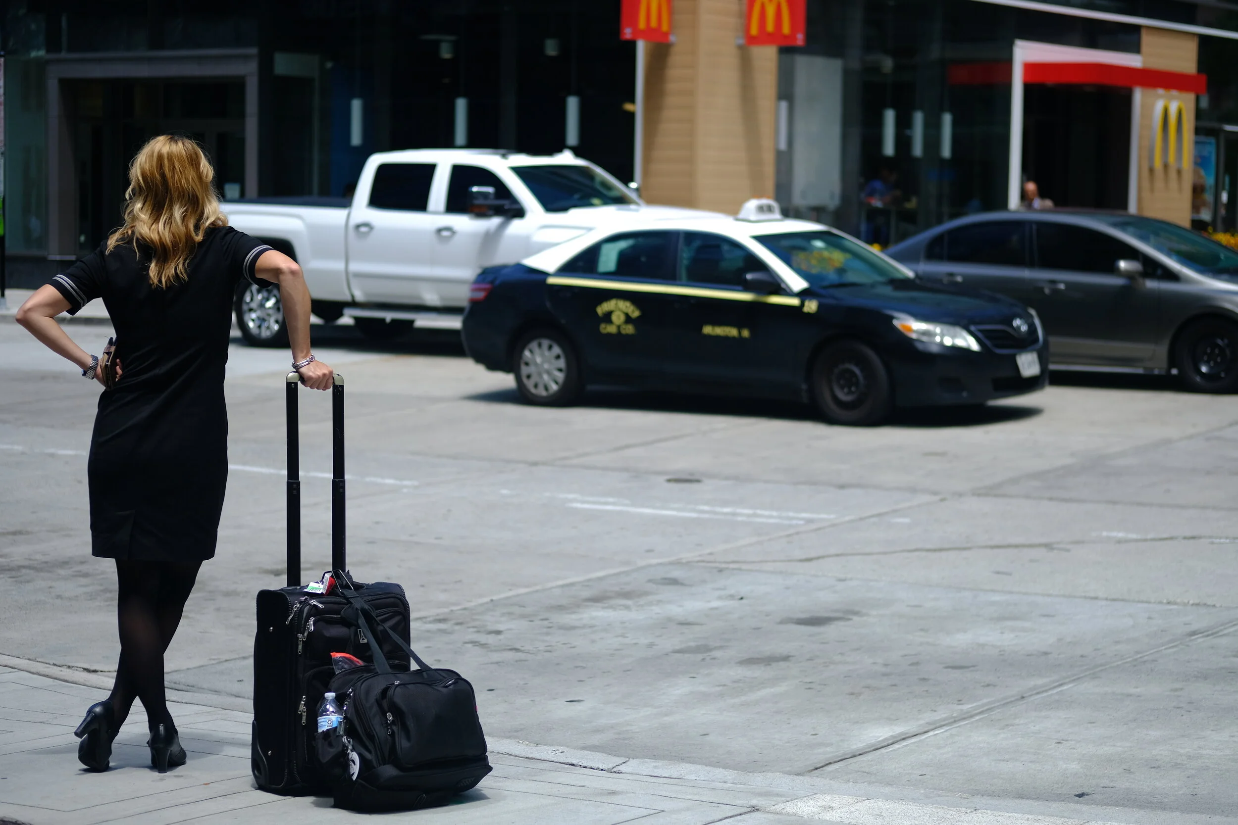  Beside bags at the precipice of the curb, leaning on telescoping handles as though life had already aged them prematurely, bones and muscles weakened, supported by the tools of a well-laden hobbler. Outfit telling on their profession, already adorne