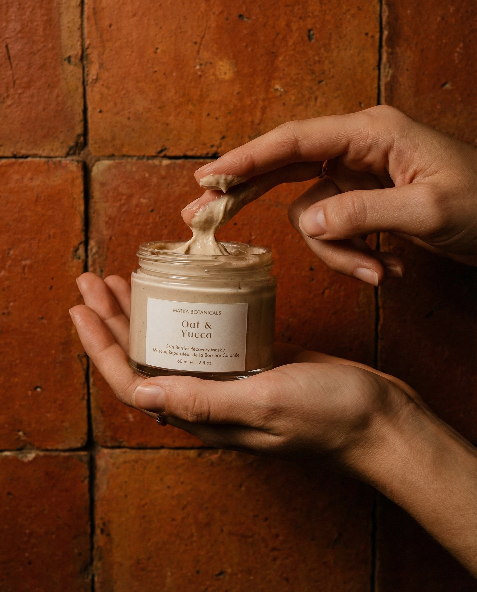Generated with Kive.ai - closeup of hand holding the jar and other hand scooping product out_ rustic terracotta tiles in background. Label text must be detailed and clear.png