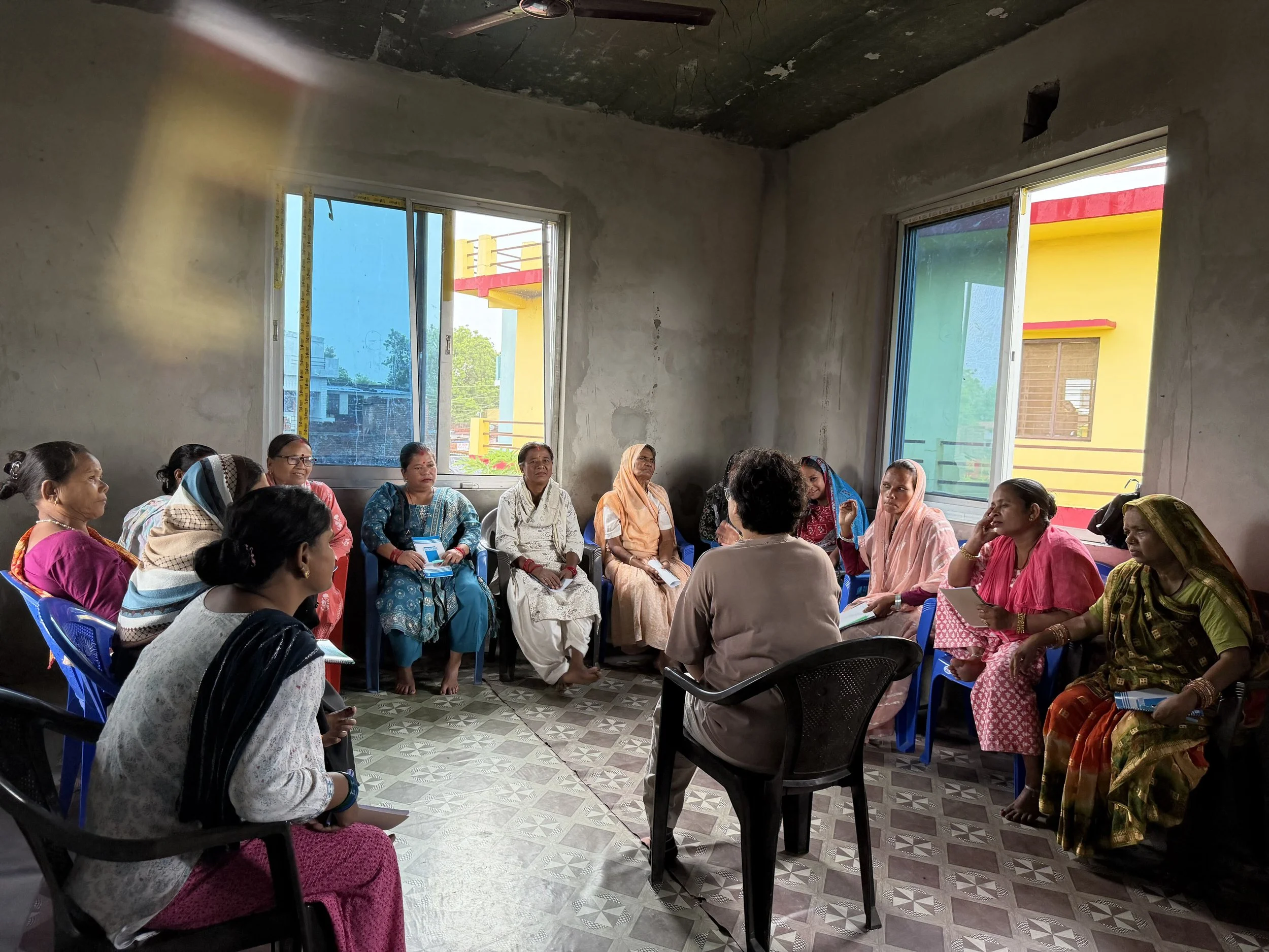 Photo of training. Women sitting in a circle with the trainers.