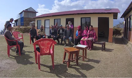 Deurali Community Committee meeting with Baseri Clinic in background.